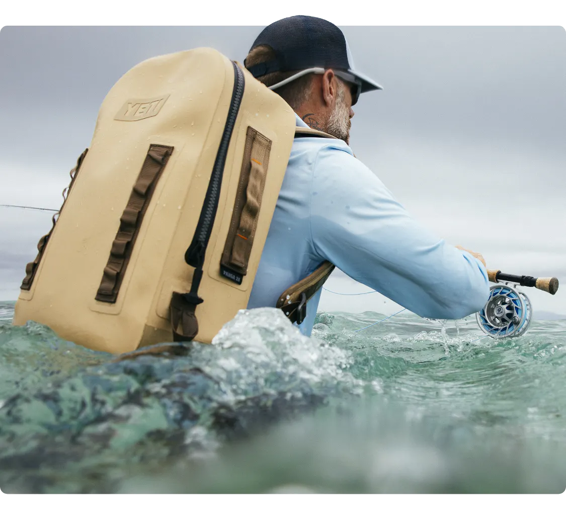 Man stood in water with a Yeti Backback
