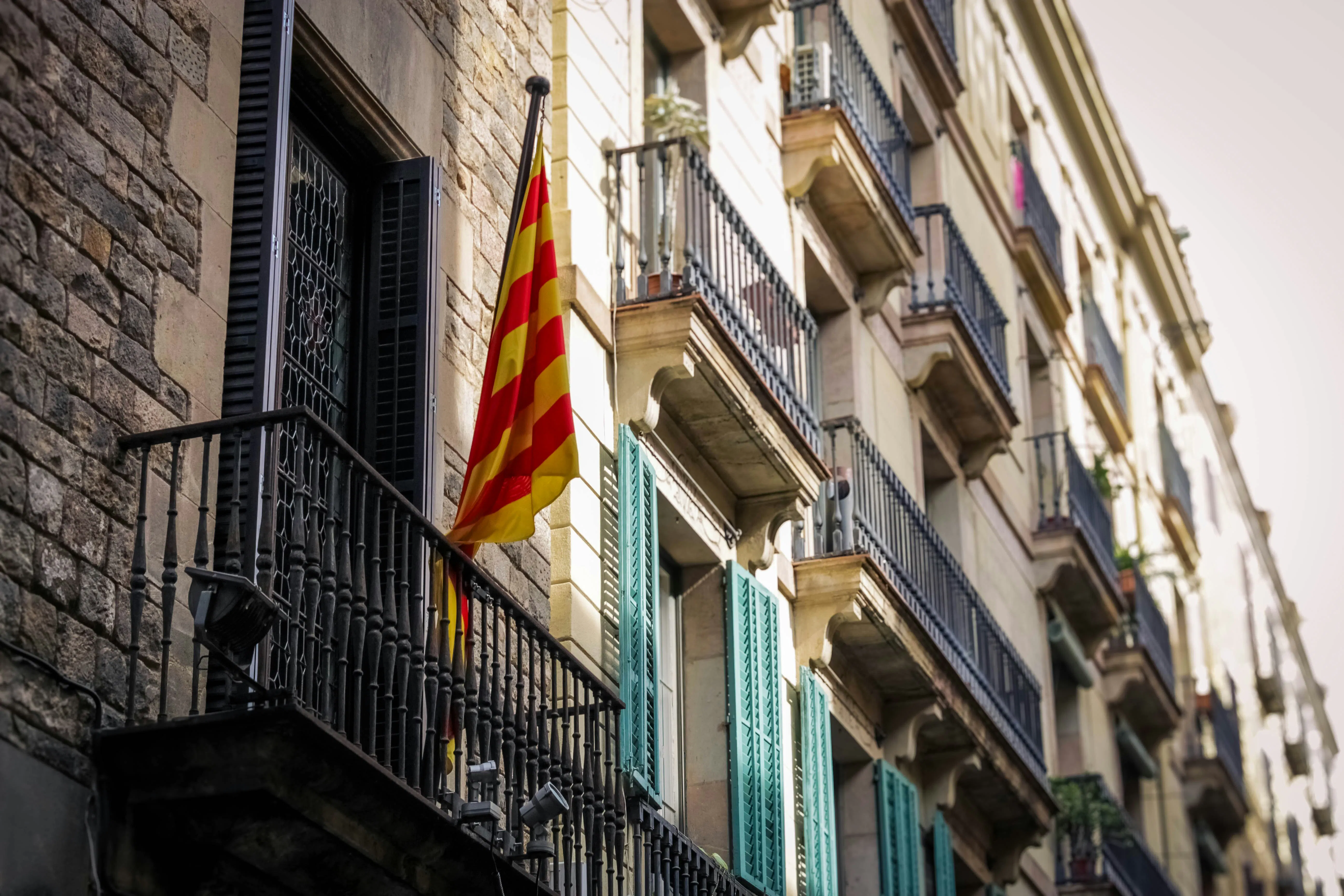 Traditionelle Wohnhausfassaden in Barcelona mit Balkonen und einer katalanischen Flagge als Symbol für den Immobilienmarkt und Hypotheken für ausländische Käufer in Katalonien.