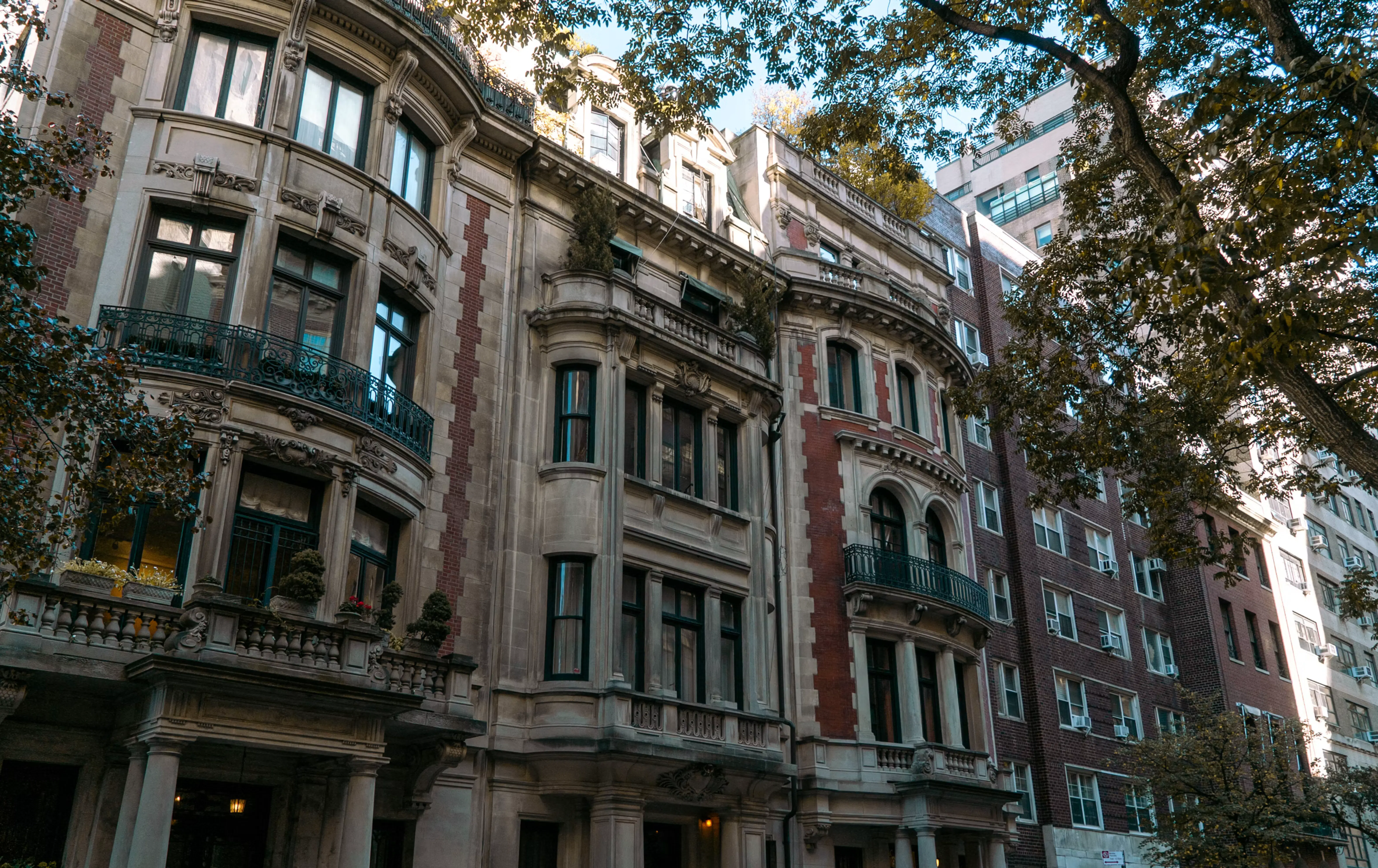 Edificis residencials històrics a Nova York amb façanes ornamentades, balcons i vistes a un carrer arbrat, reflectint el mercat immobiliari de luxe de la ciutat