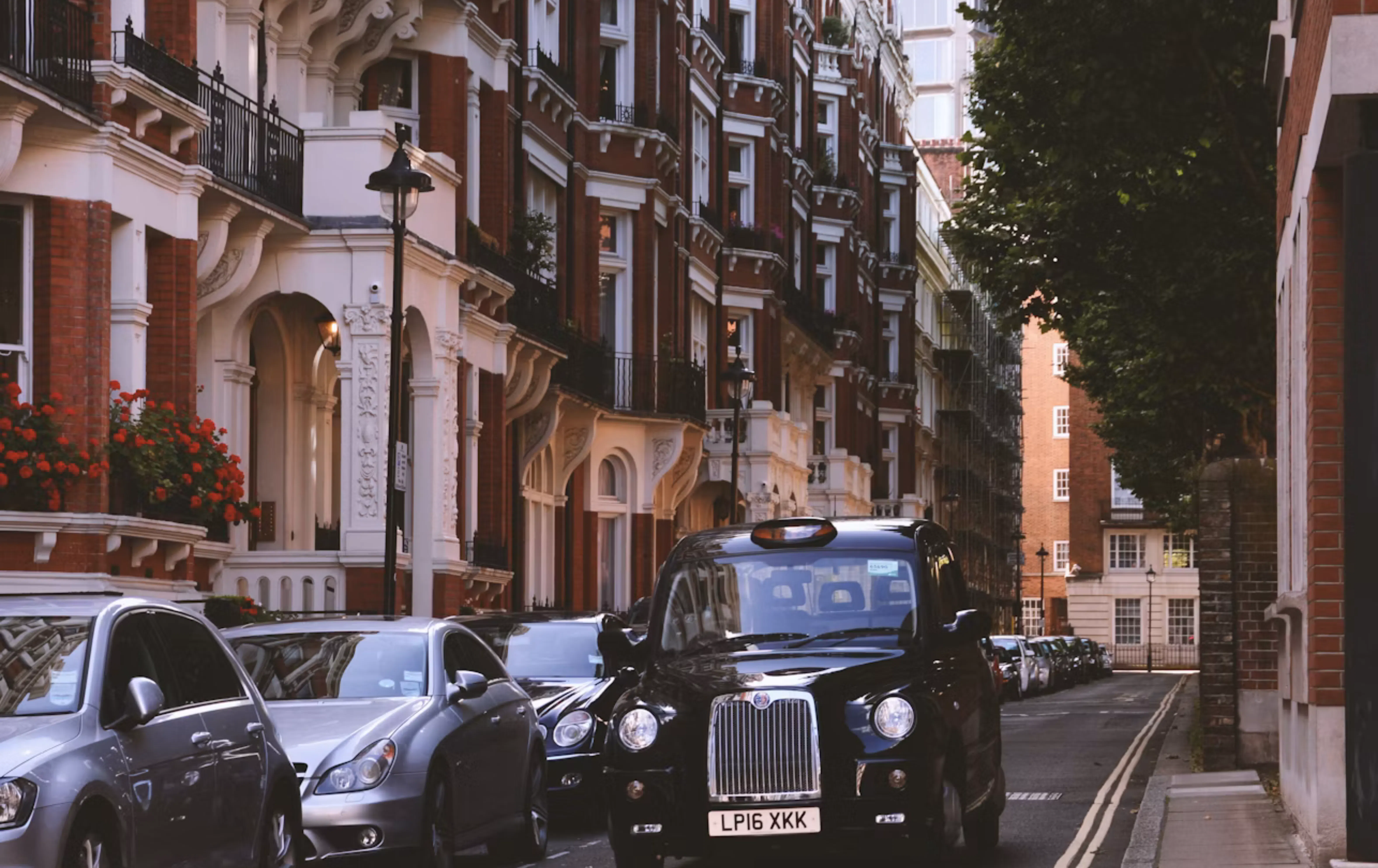 Carrer residencial a Londres amb cases històriques de maó, cotxes aparcats i un taxi negre, reflectint el mercat immobiliari urbà de la ciutat.