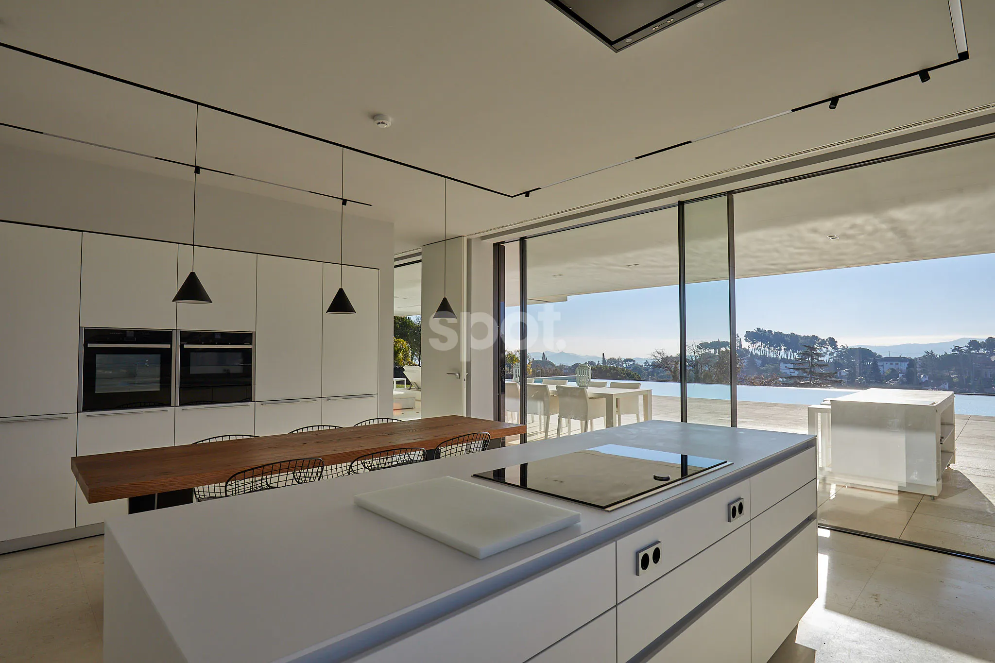 Localización de rodaje en una cocina de villa moderna en España con diseño abierto, vistas al mar, puertas de cristal, terraza, interiores minimalistas y luz natural.