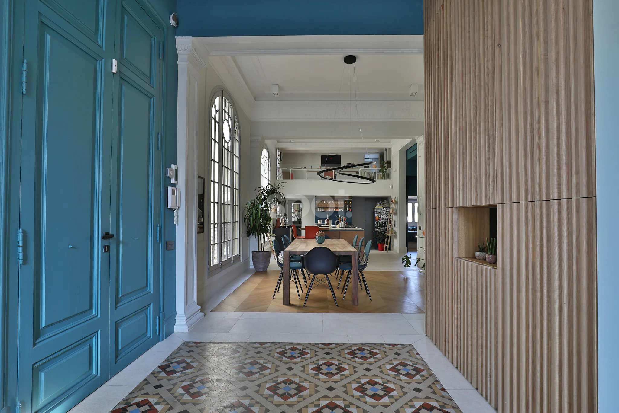Elegant apartment filming location in Barcelona with blue doors, patterned tile flooring, high ceilings, arched windows and a modern dining area.