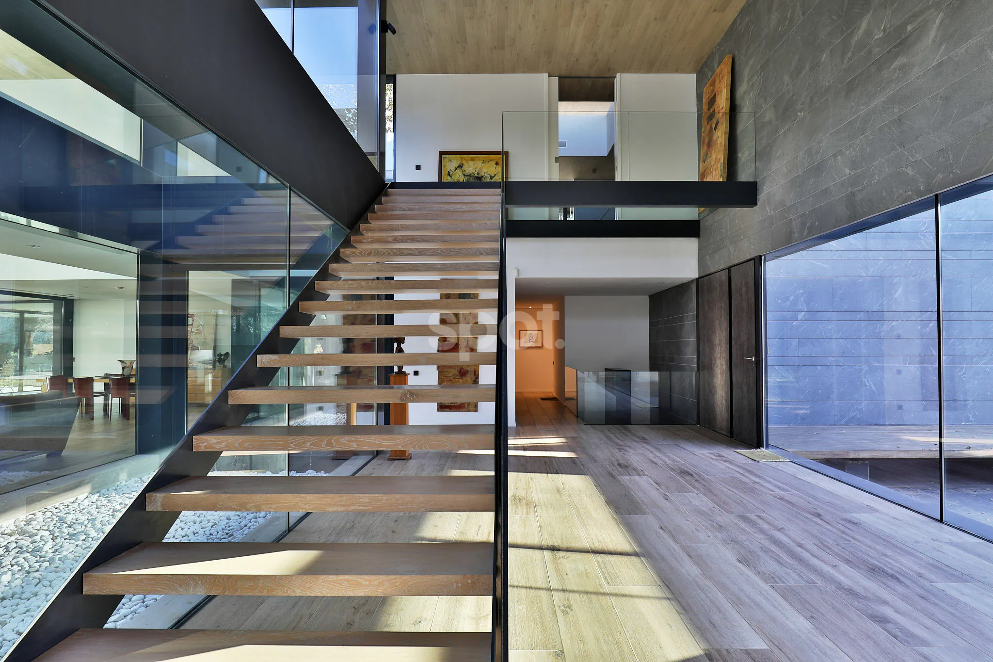 El interior de una villa minimalista contemporánea con una gran escalera de madera y acero, enormes fachadas de vidrio, líneas limpias y luz natural para proyectos audiovisuales.