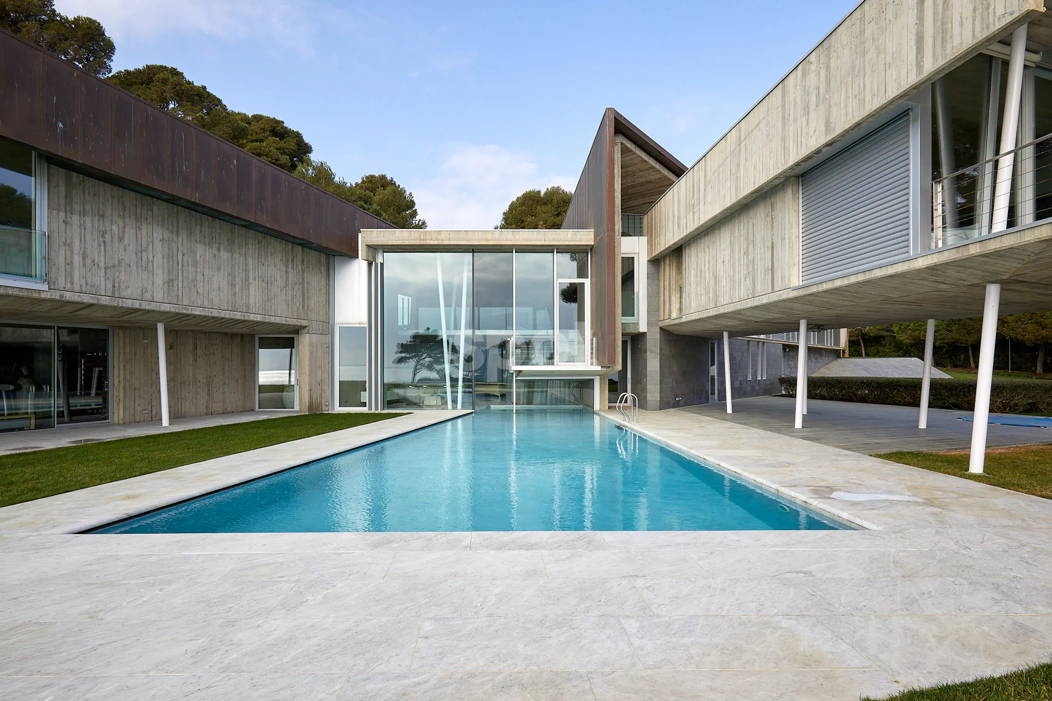 Modern villa filming location in Spain with swimming pool, concrete architecture, glass walls, open terrace and landscaped outdoor space.