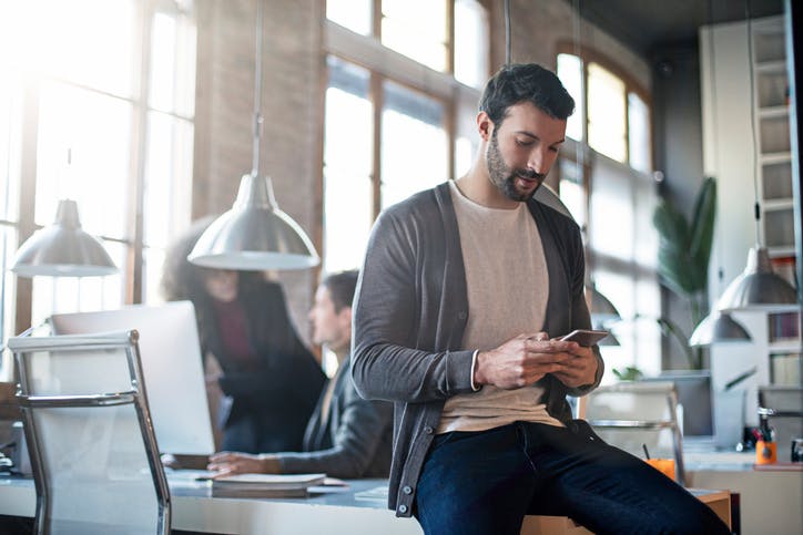 man sitting on a desk in the office on his phone