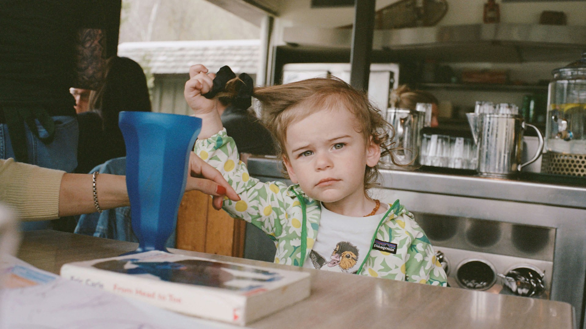 little boy sitting at a table playing with his hair