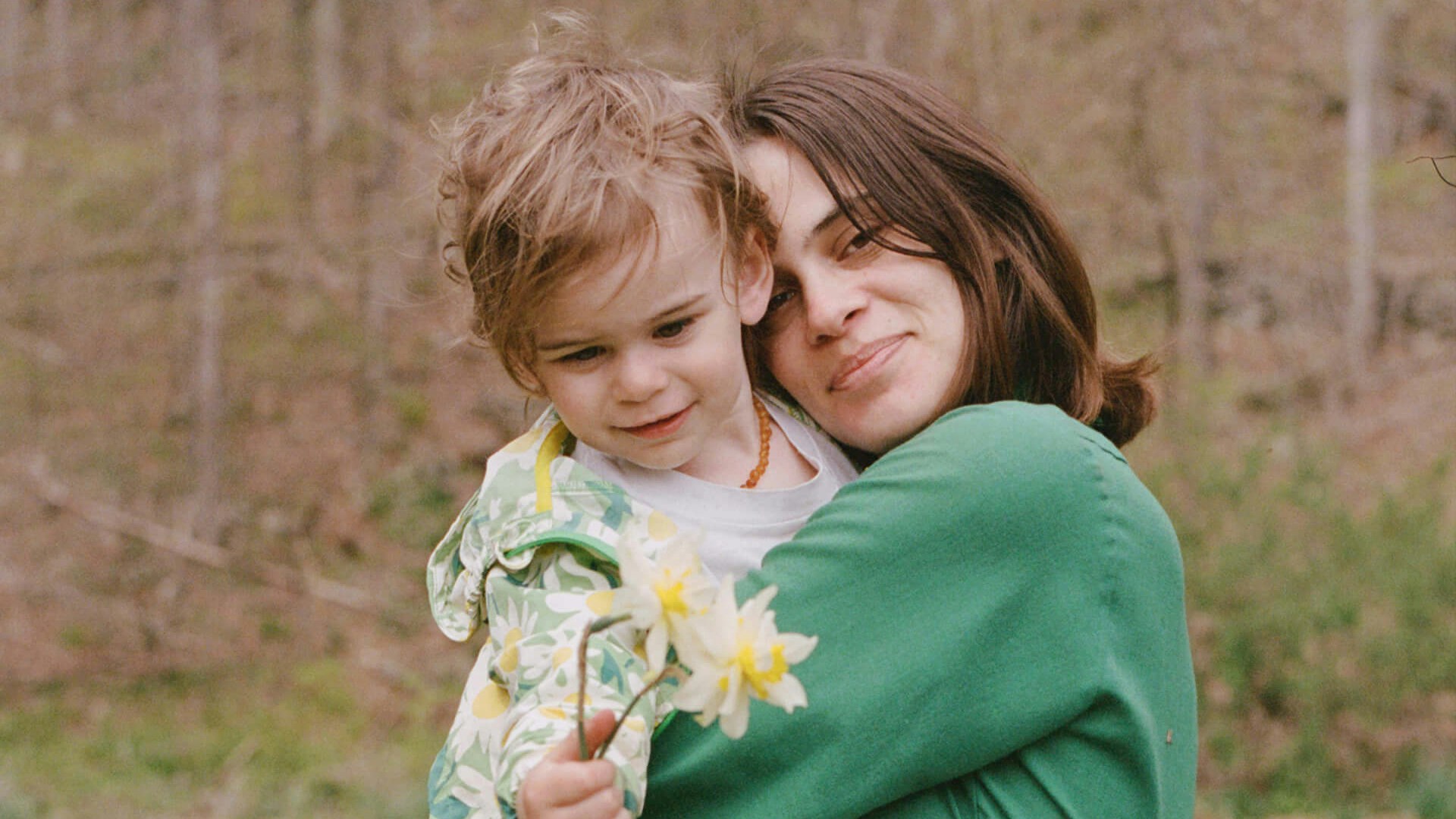 mom hugging son holding a flower
