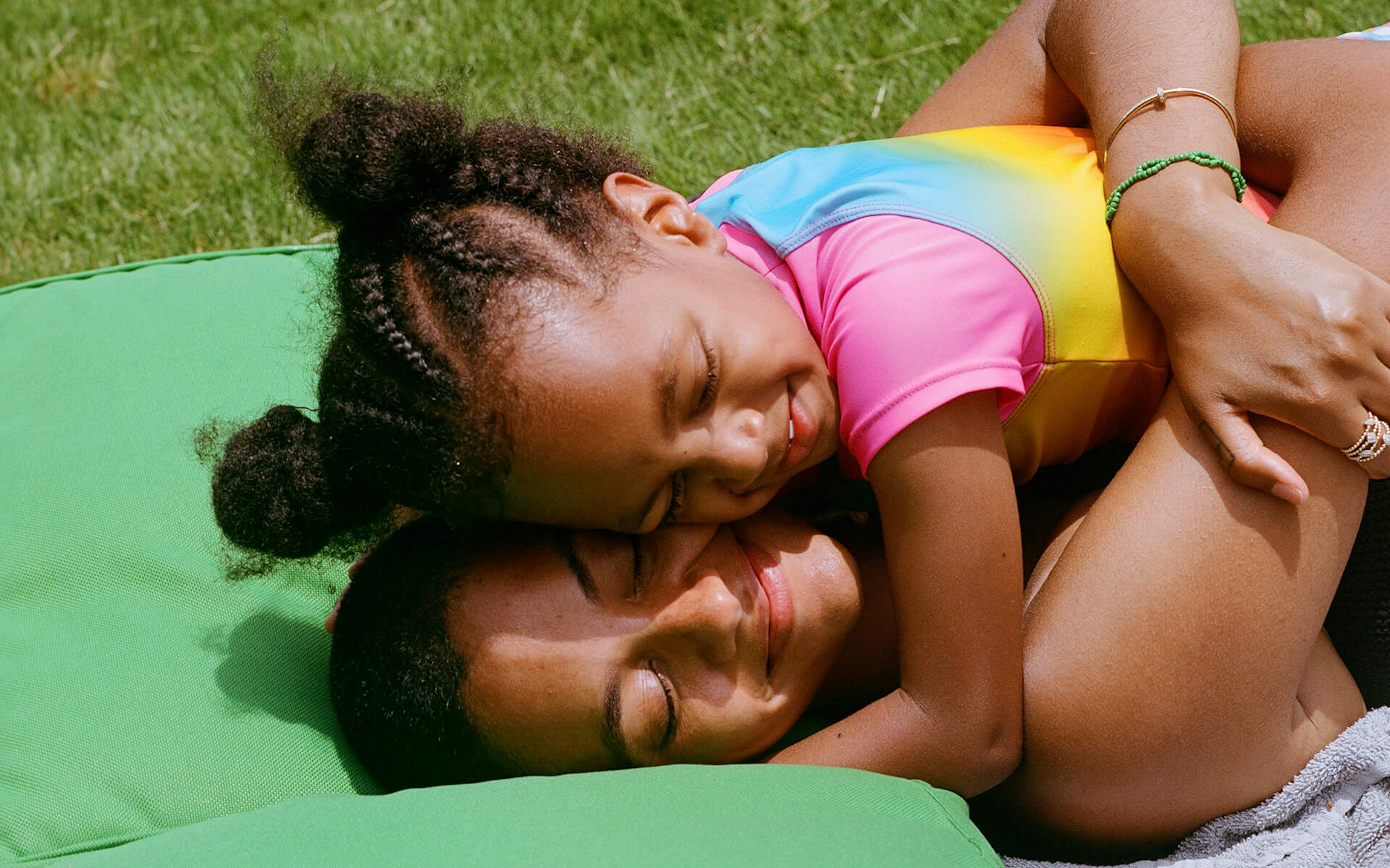 mom hugging her daughter on a blanket in the grass