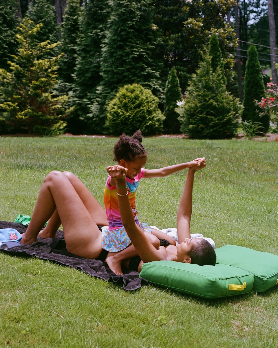 daughter sitting on mom on blanket outside