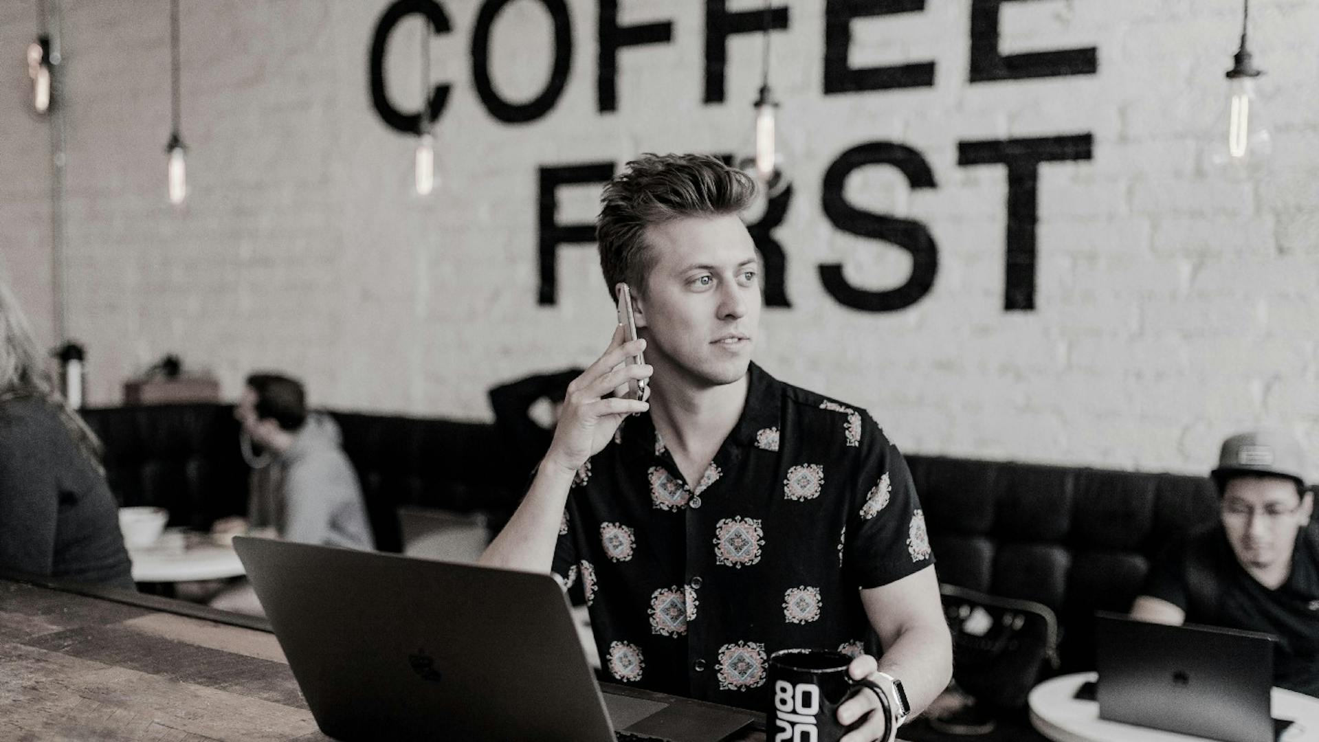 Coffee shop owner working on a laptop and talking on the phone