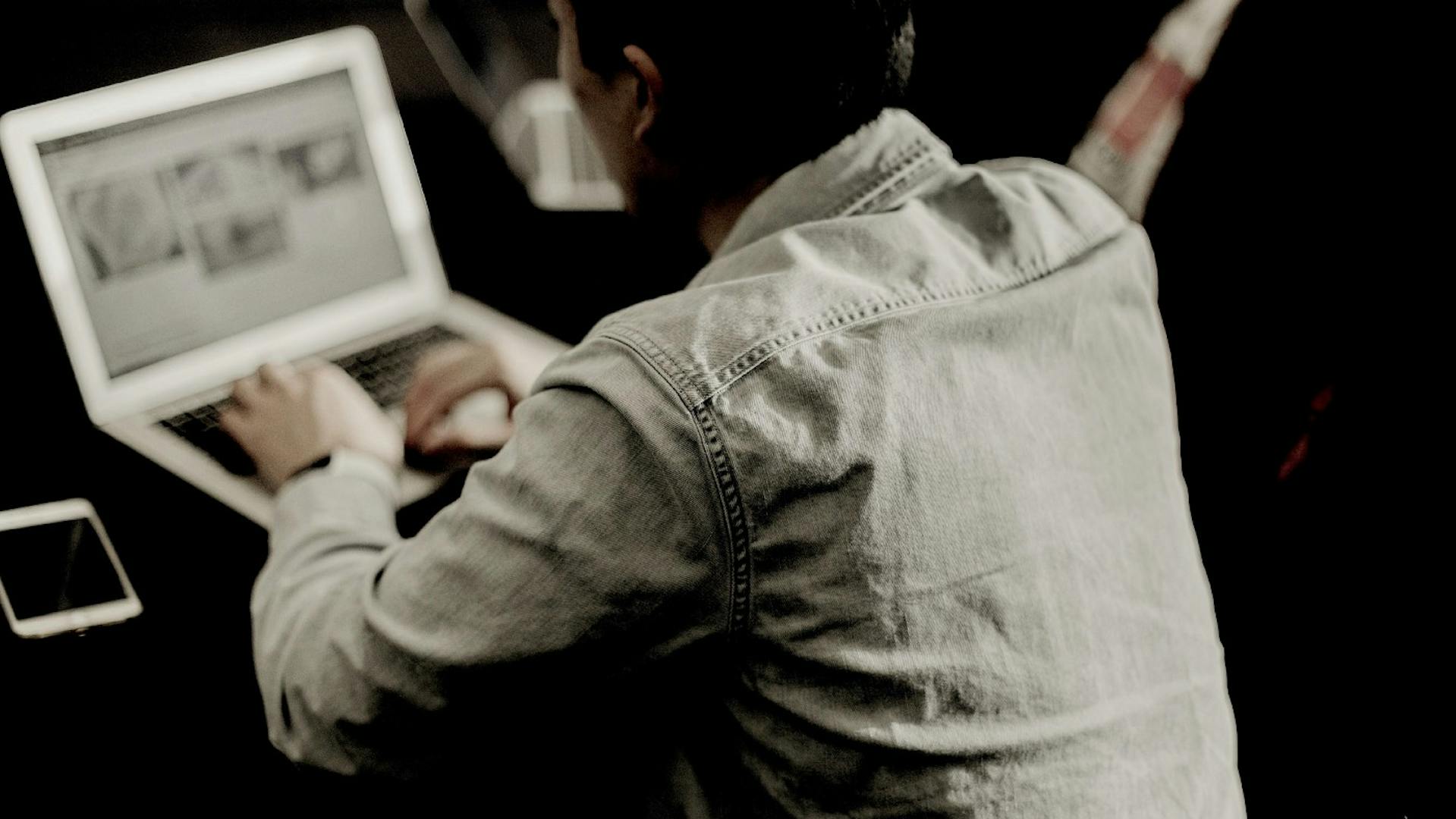 Man in a work meeting working on a laptop