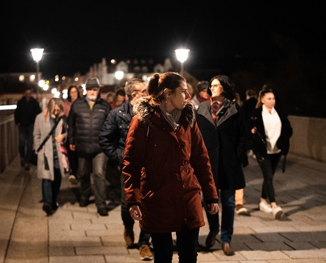 Guide läuft mit der Gruppe bei Nacht über die Steinerne Brücke.