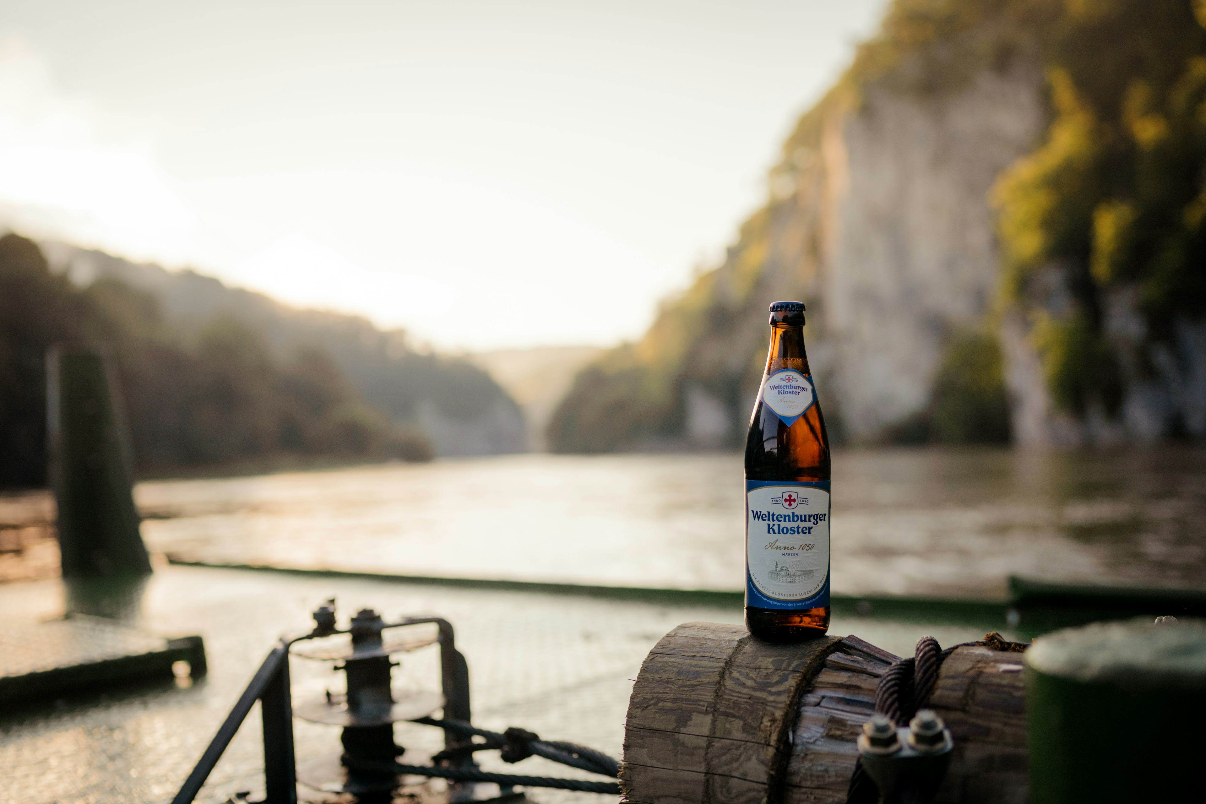 Eine Flasche Weltenburger Bier im Vordergrund und im Hintergrund der Donaudruchbruch in Weltenburg