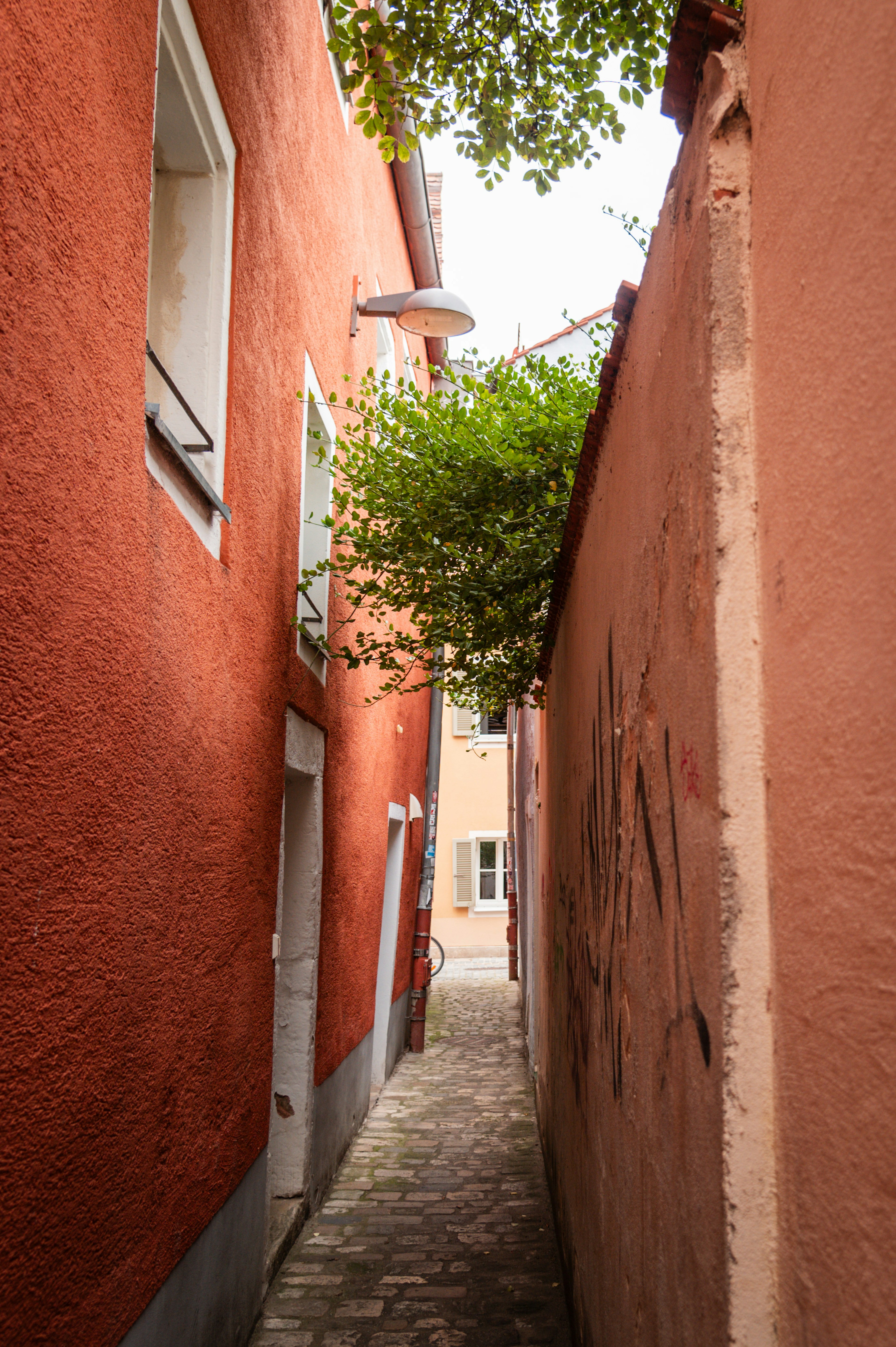 Eine der schmalsten Gassen in Regensburg, links ein rotes, rechts ein lachsfarbenes Haus