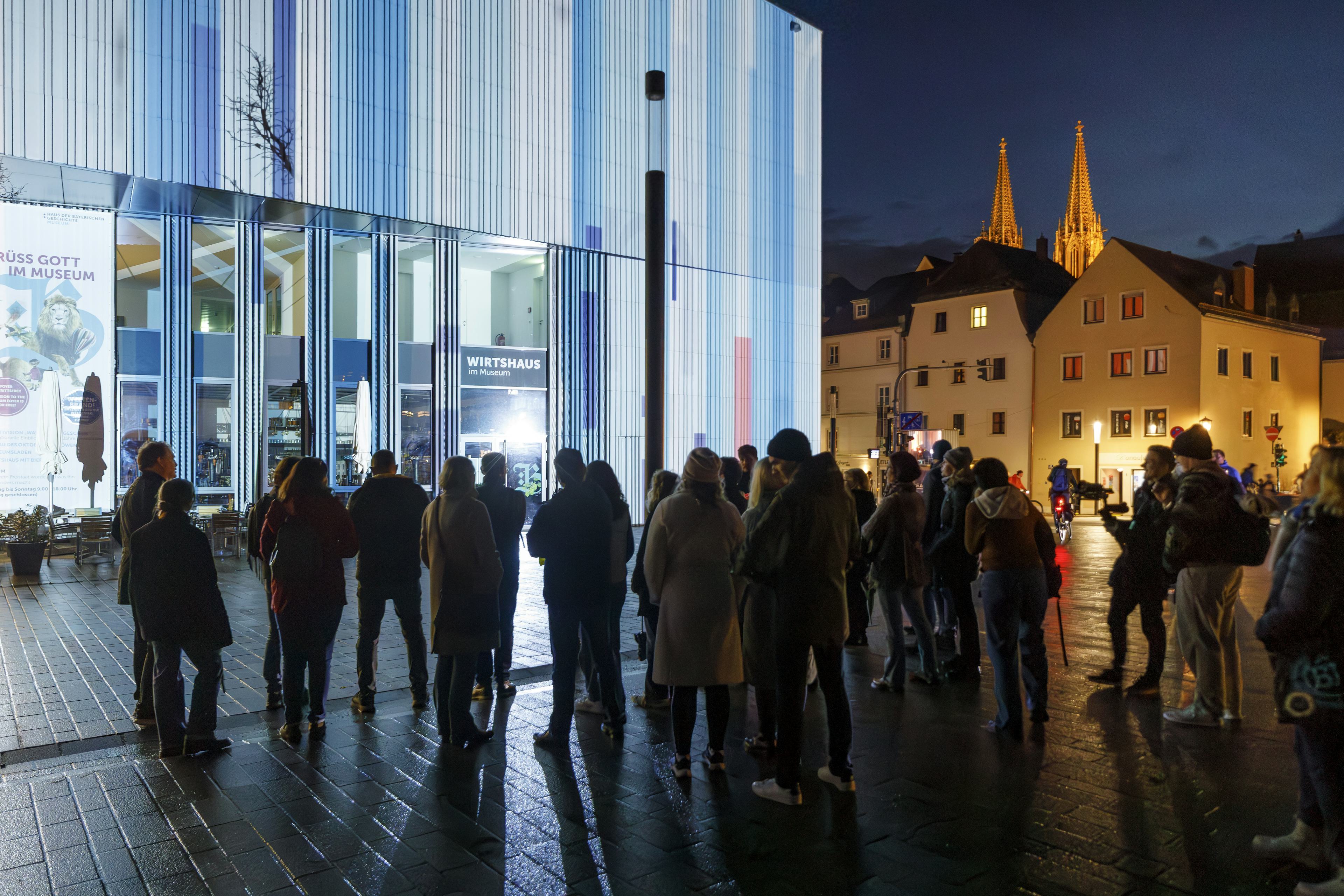 Eine Gruppe von Teilnehmern der Führung vorm beleuchteten Haus der bayerischen Geschichte