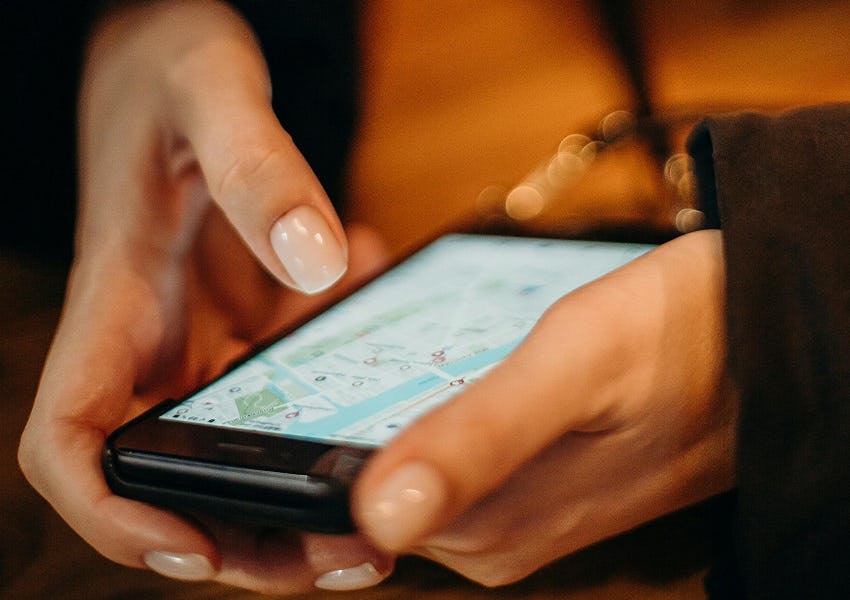 Nahaufnahme von Händen, die ein Handy halten und etwas auf dem Display tippen