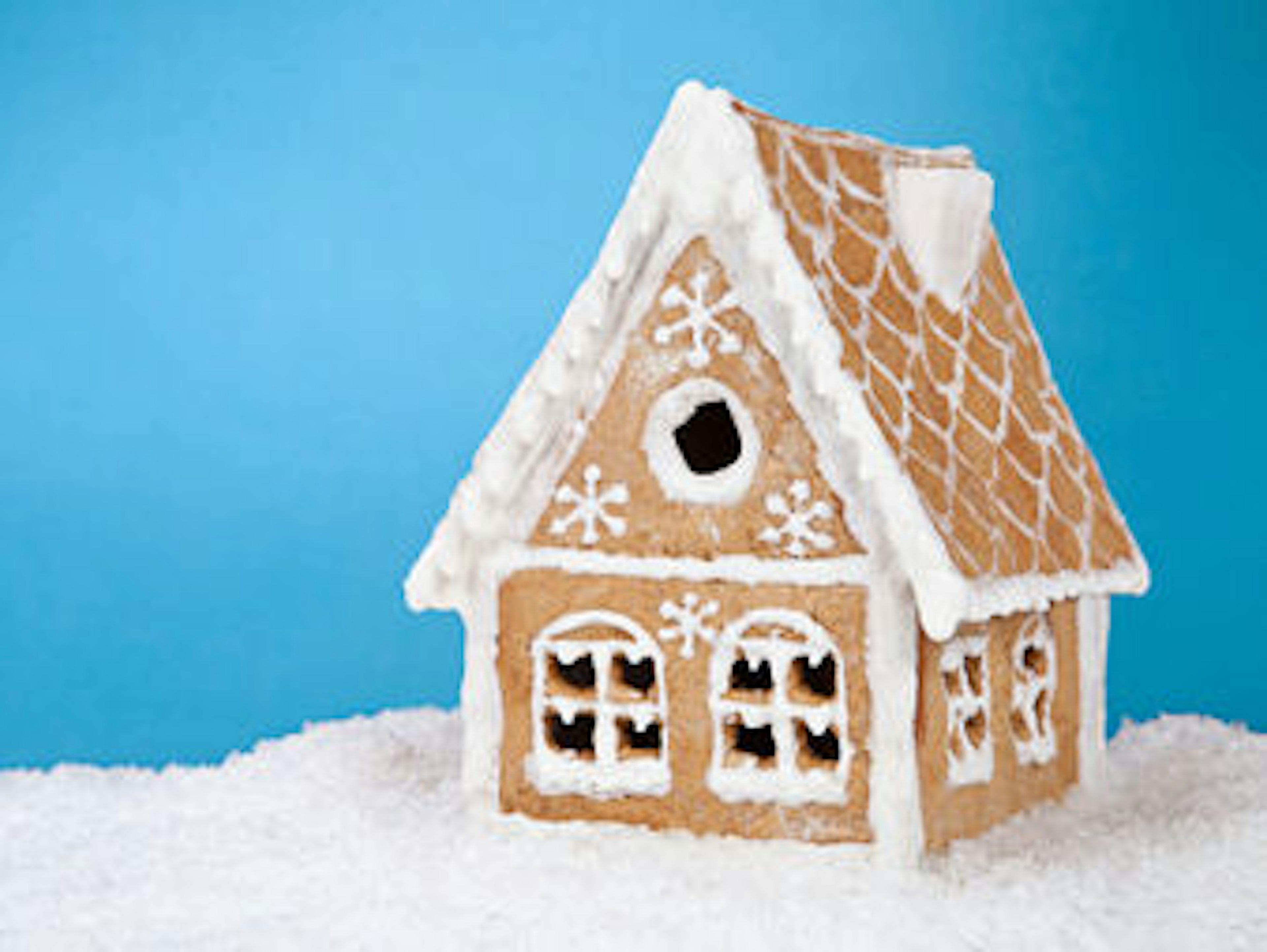 Lebkuchenhaus vor blauem Hintergrund im Schnee