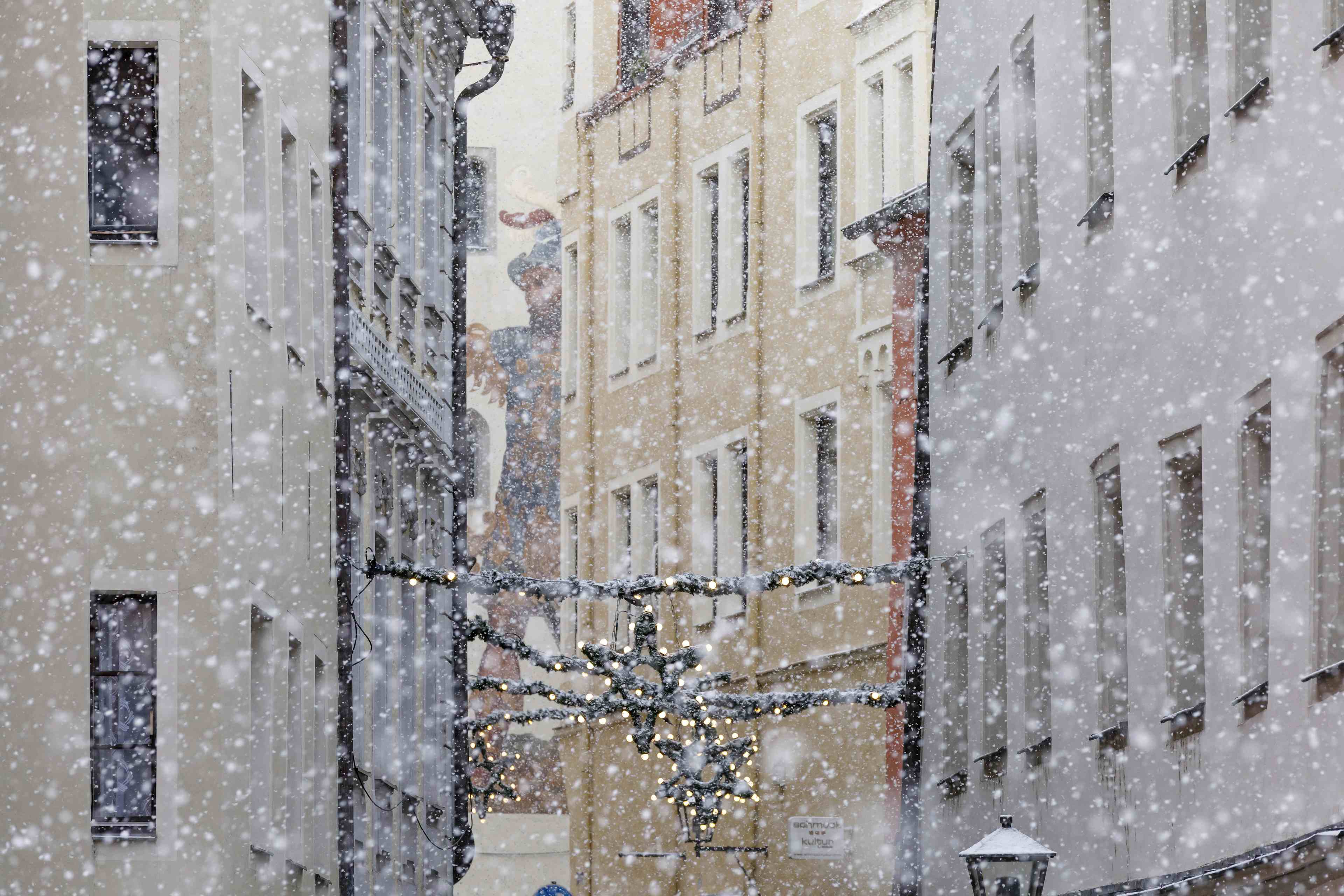 Gasse in Regensburg bei Schneefall mit Girlanden zwischen den Häusern gespannt.