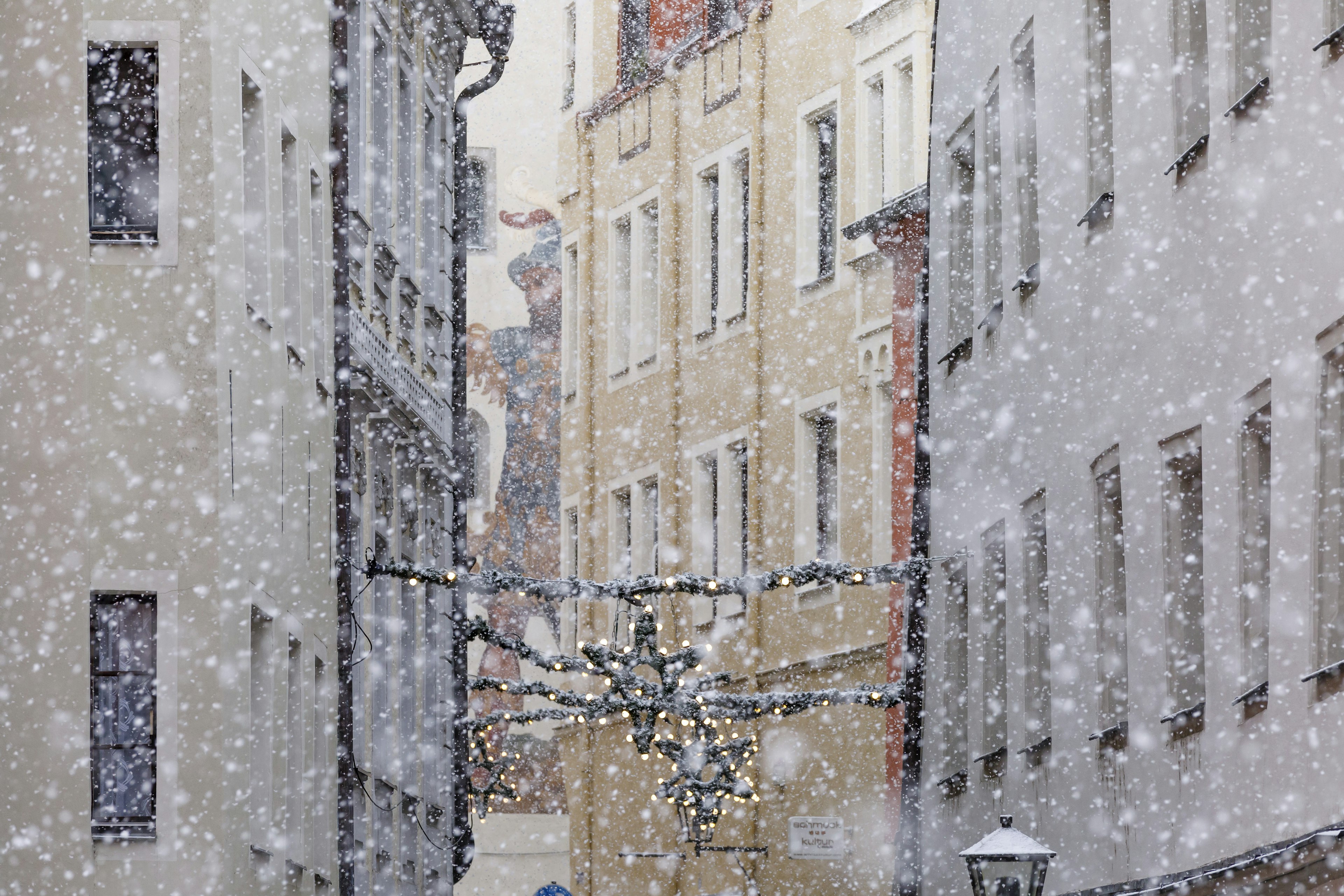 Gasse in Regensburg bei Schneefall mit Girlanden zwischen den Häusern gespannt.