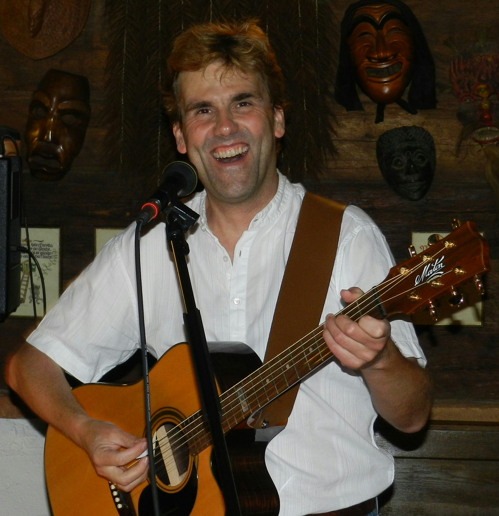 Peter Reichl mit der Gitarre lacht in die Kamera