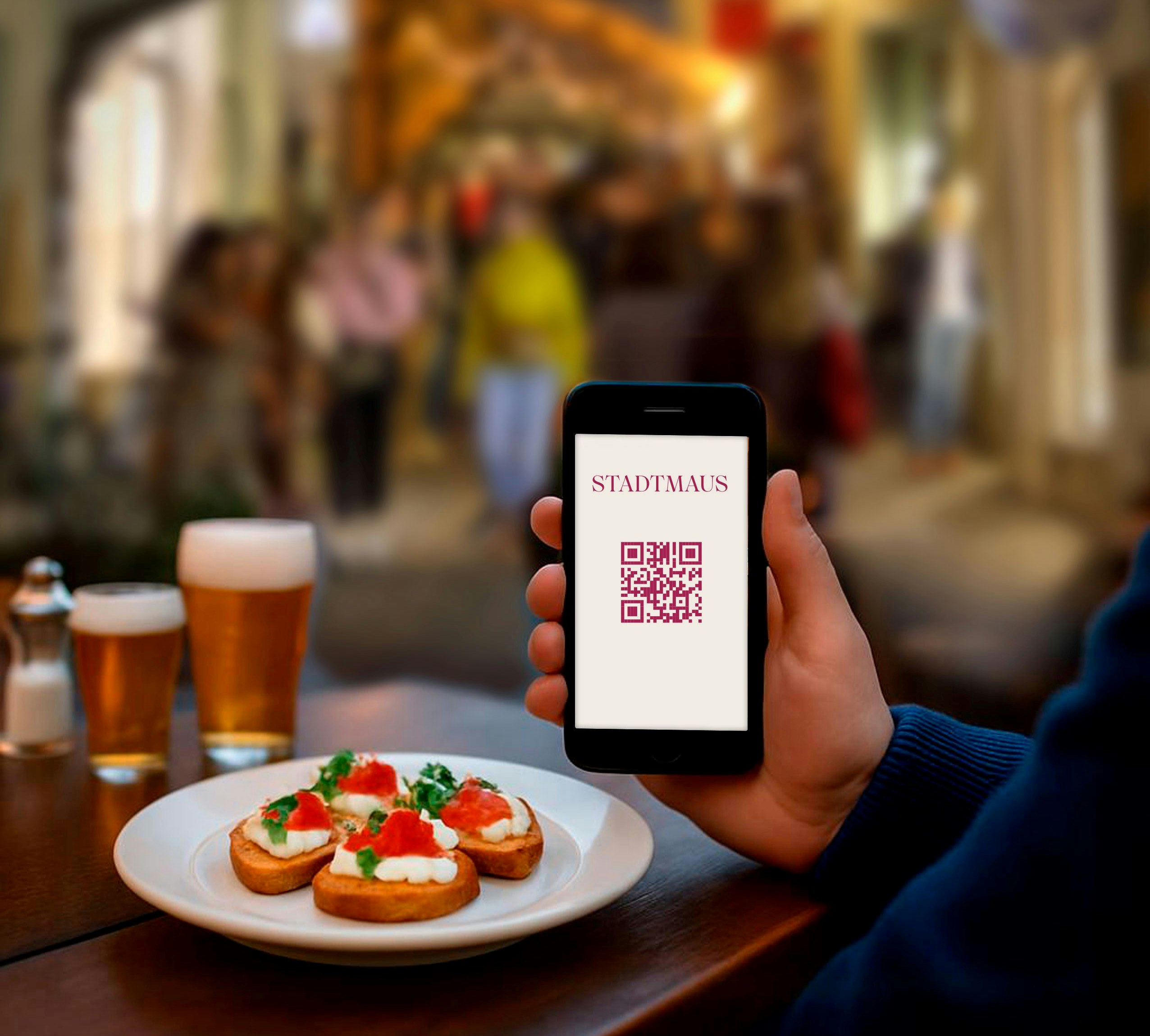 Teller mit Bruscetta, Bier, Handybildschirm auf dem ein QR Code zu sehen ist.