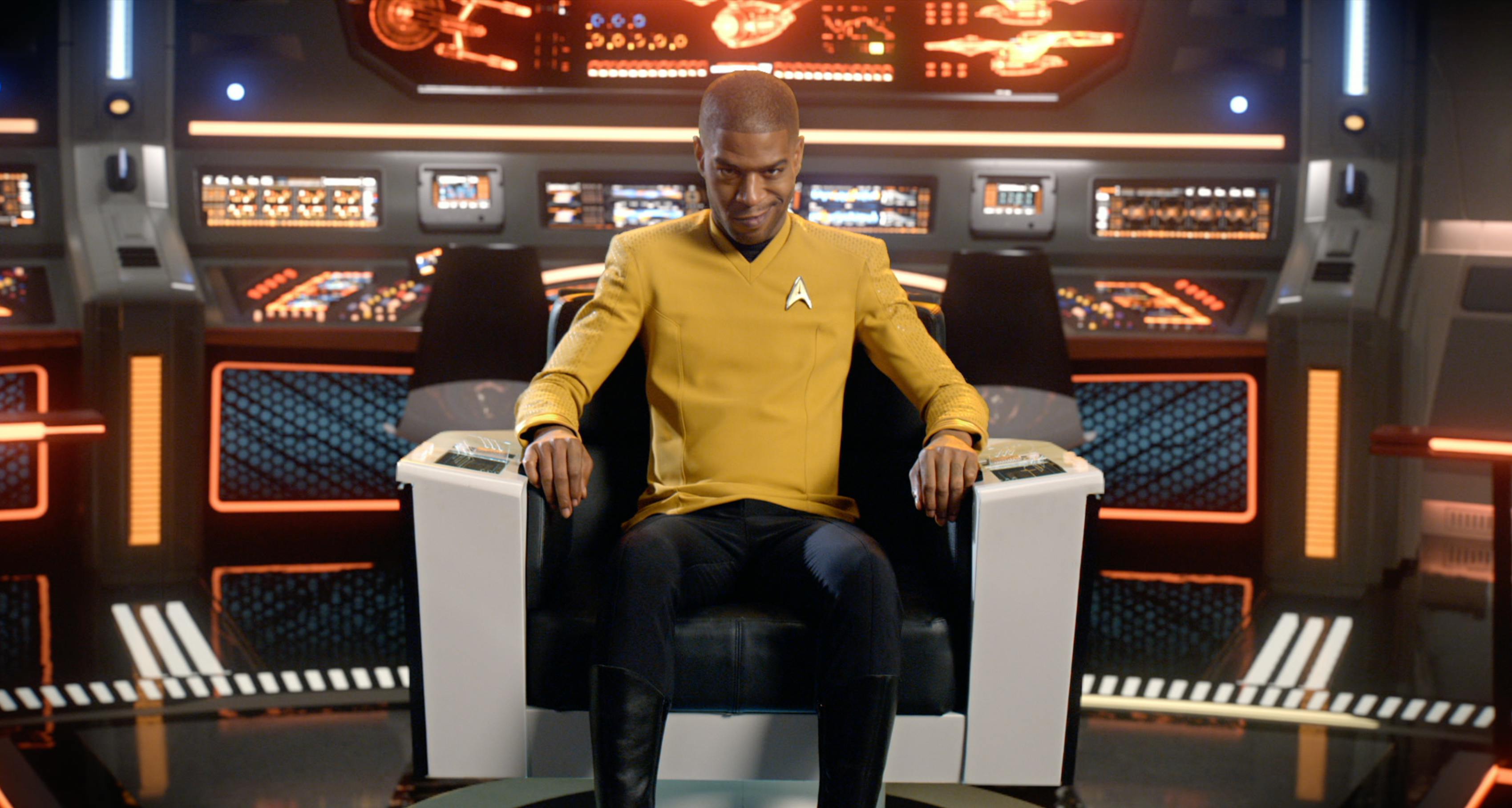 Scott Mescudi (Kid Cudi) in a Starfleet uniform sits  at the captain's chair on the bridge of the Enterprise and narrows his gaze intensely in front of him