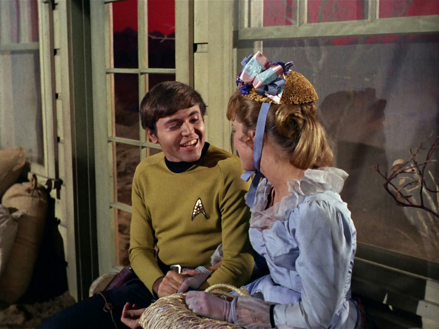 Outside of the bar, Chekov as Billy Claiborne and Sylvia enjoy a romantic interlude while clasping hands in 'Spectre of the Gun'