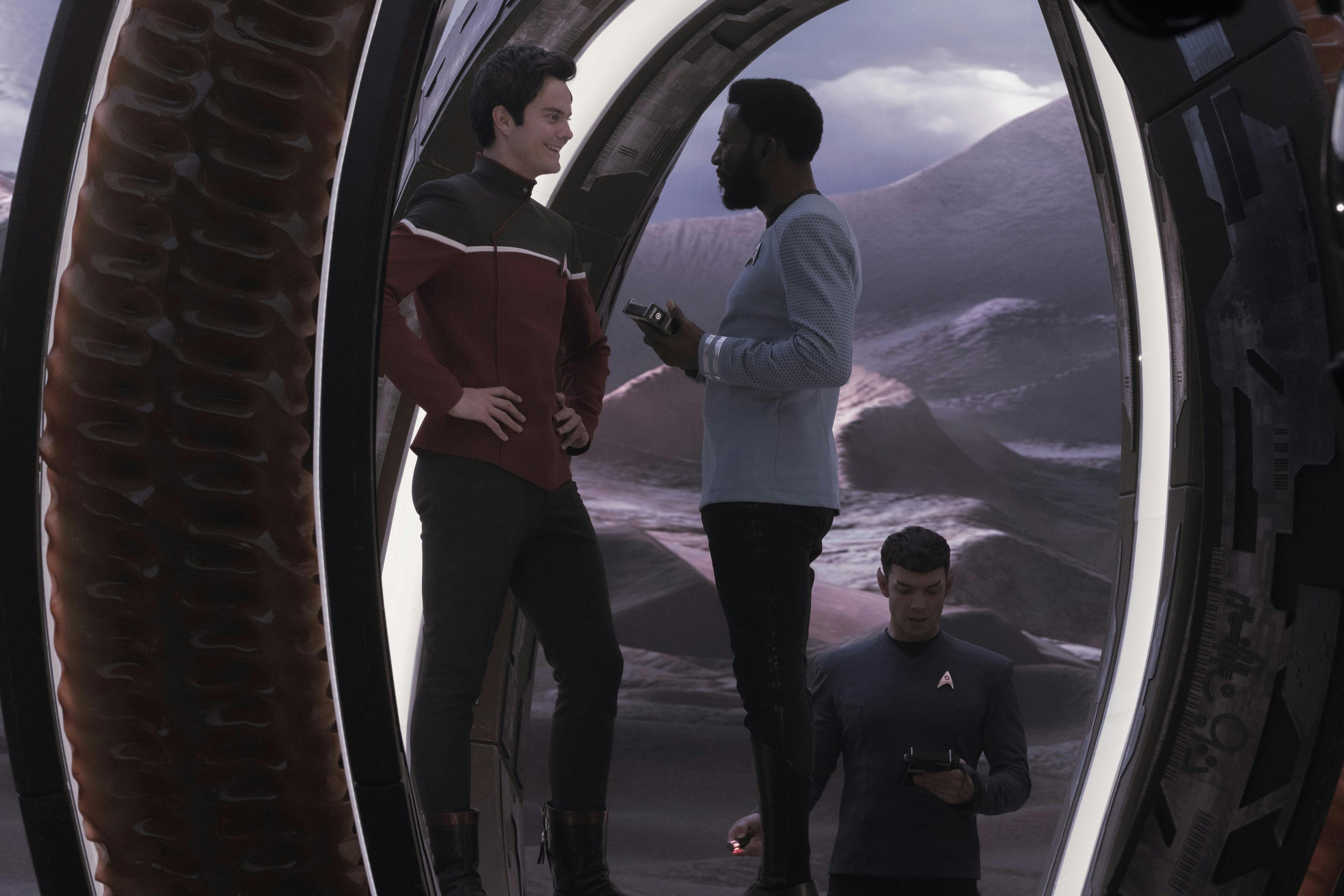 Boimler smiles with his hands on his hips admiring Dr. M'Benga's tricorder as Spock scans the Krulmuth-B portal in 'Those Old Scientists'