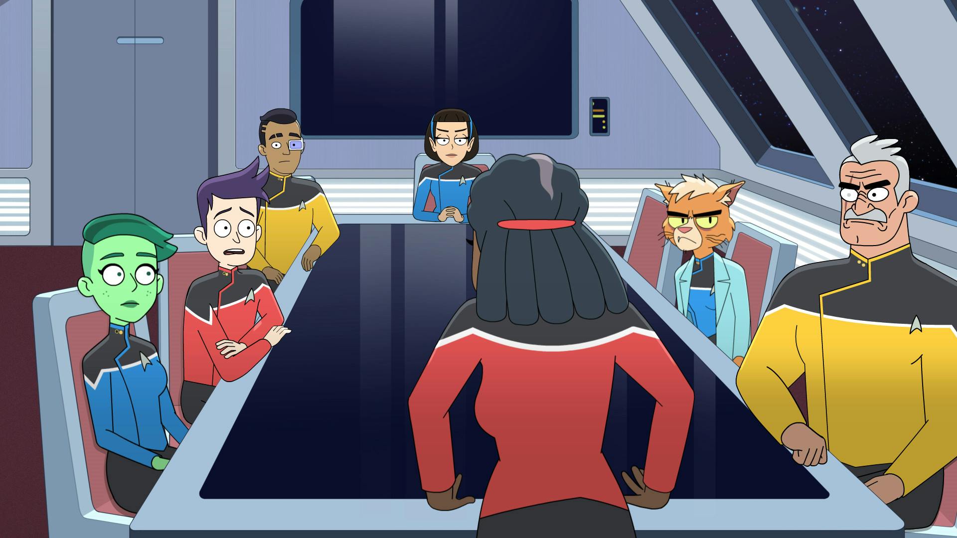 Standing at the head of the conference room table, Captain Freeman leans over with both hands planted on the table with Tendi, Boimler, Rutherford, T'Lyn, Dr. T'Ana and Shaxs seated around