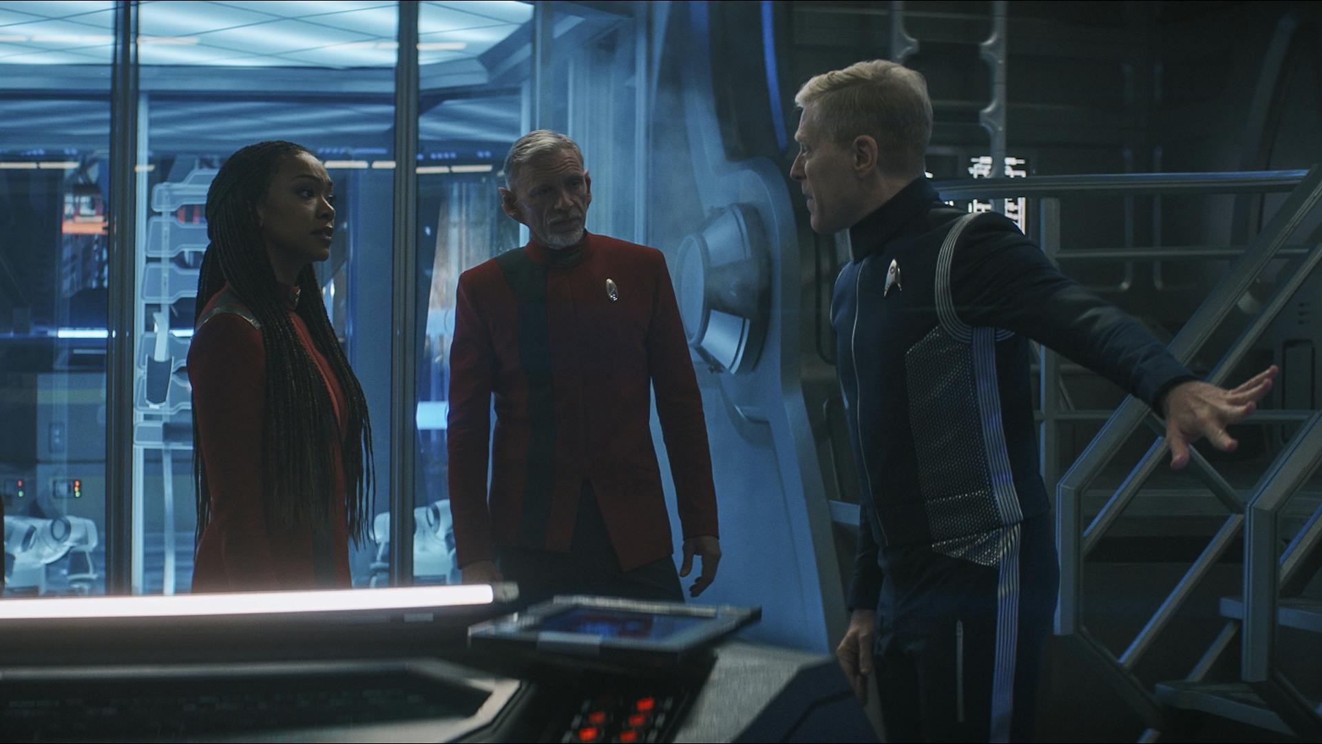 Convening in Engineering, Paul Stamets in Discovery's 23rd Century uniform addresses Rayner and Burnham in 32nd Century uniforms in 'Face the Strange'
