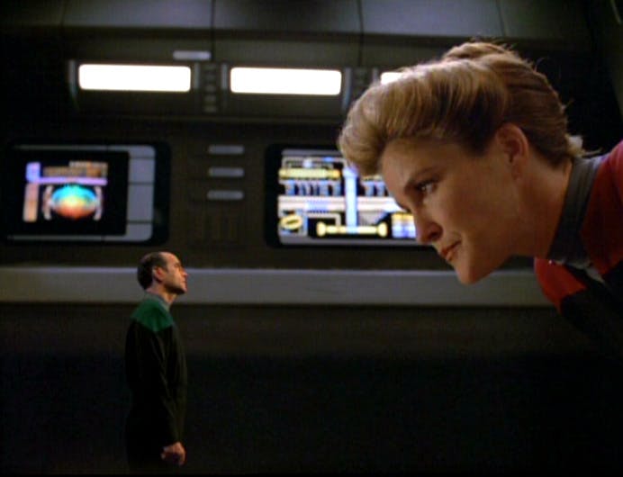 Captain Janeway bends down to peer at the miniaturized EMH, The Doctor, in 'Persistence of Vision' 