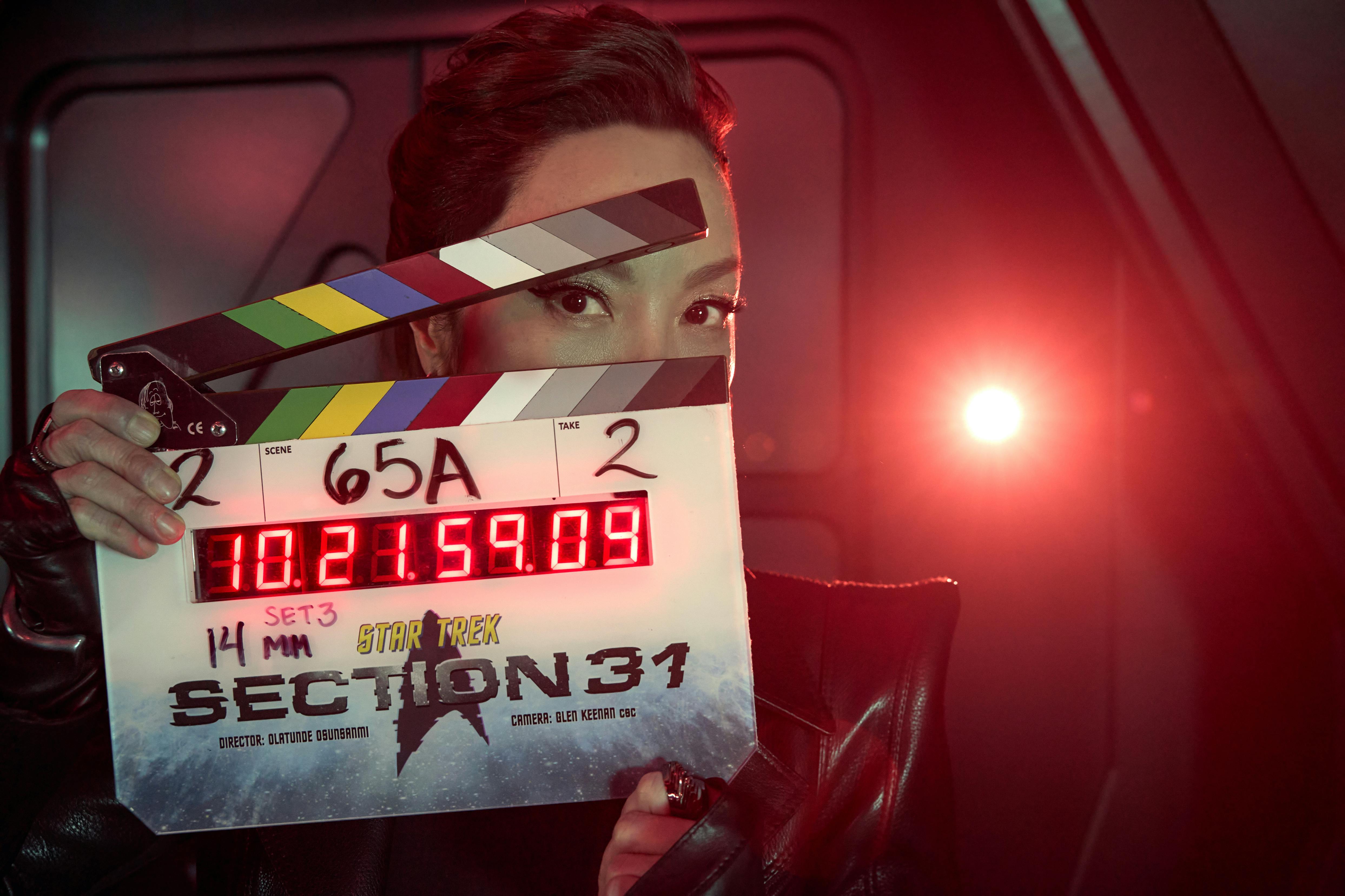 Michelle Yeoh in costume as Philip Georgiou holds a clapboard marking the production of Star Trek: Section 31