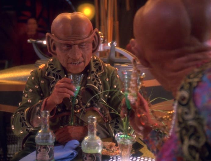 Nilva dines with Quark masquerading as Lumba enjoying several bottles of Slug-o-Cola in Quark's Bar in 'Profit and Lace'