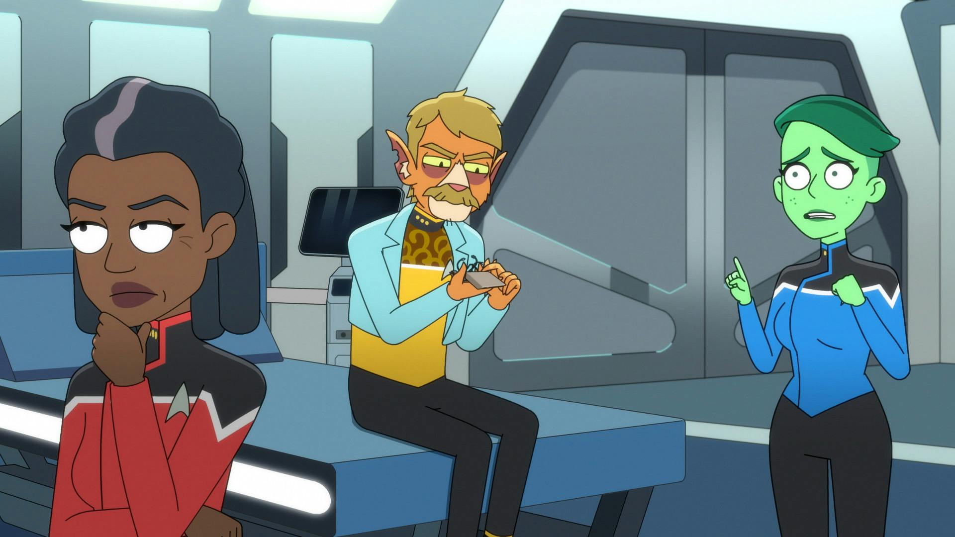 In Sickbay, Captain Carol Freeman, considering the situation, has her backed turned to T'Illups who is sitting on the bio-bed looking over a tricorder while Tendi apprehensively raises her finger to say something to Freeman in 'Twovix'