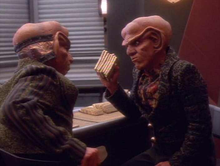 Quark lifts a stack of latinum and raises it in front of Rom in 'The Homecoming'
