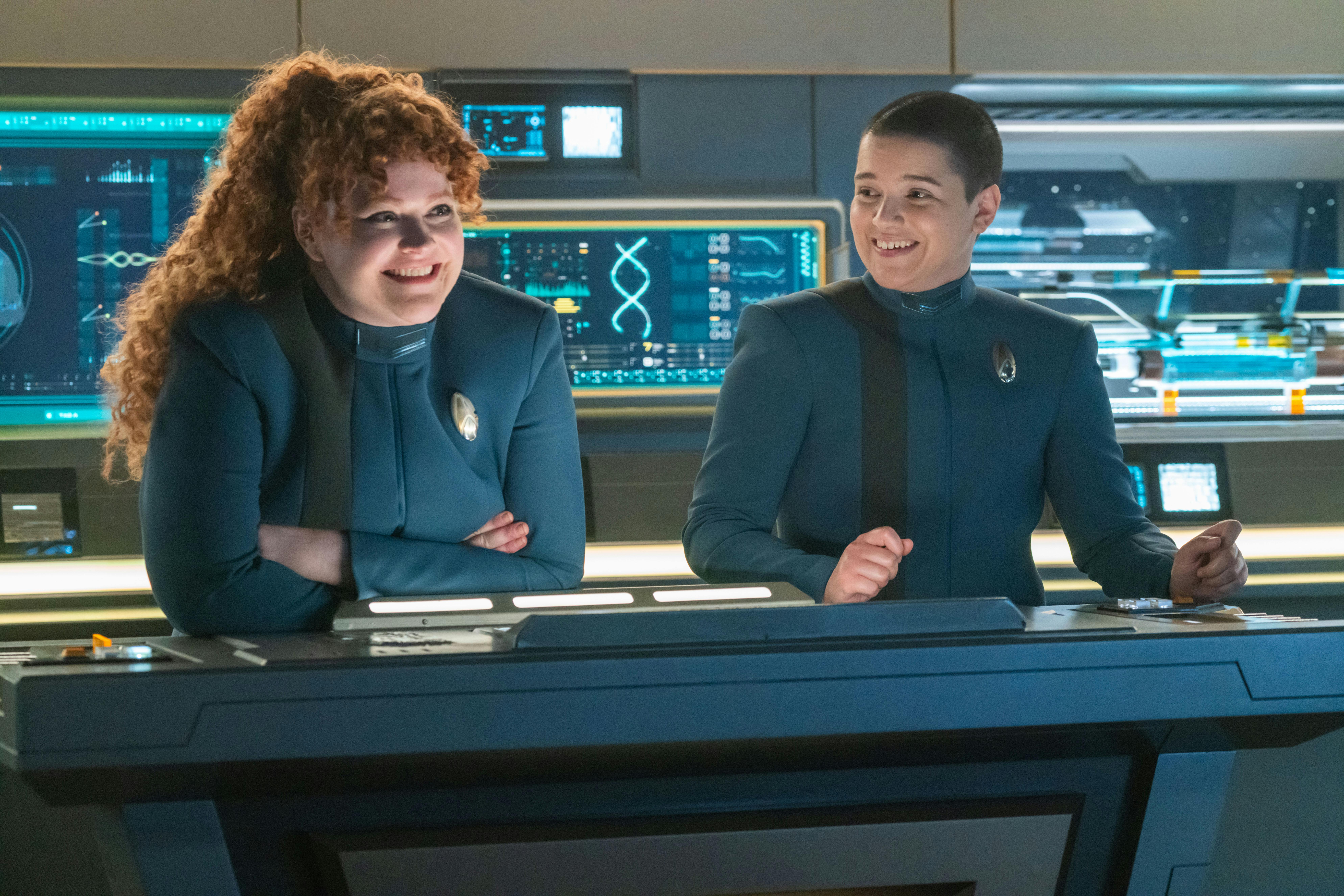 Tilly and Adira are smiling and in good spirits as they lean towards a computer panel in the Science Lab in 'Erigah'