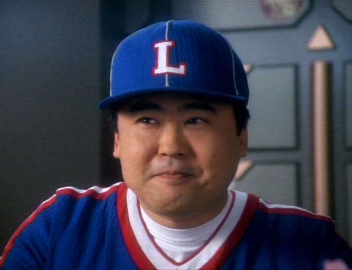 Close-up of holo-baseball player Buck Bokai, wearing his Kings gear, looking to his right and smiling with his eyes in Star Trek: Deep Space Nine's 'If Wishes Were Horses'