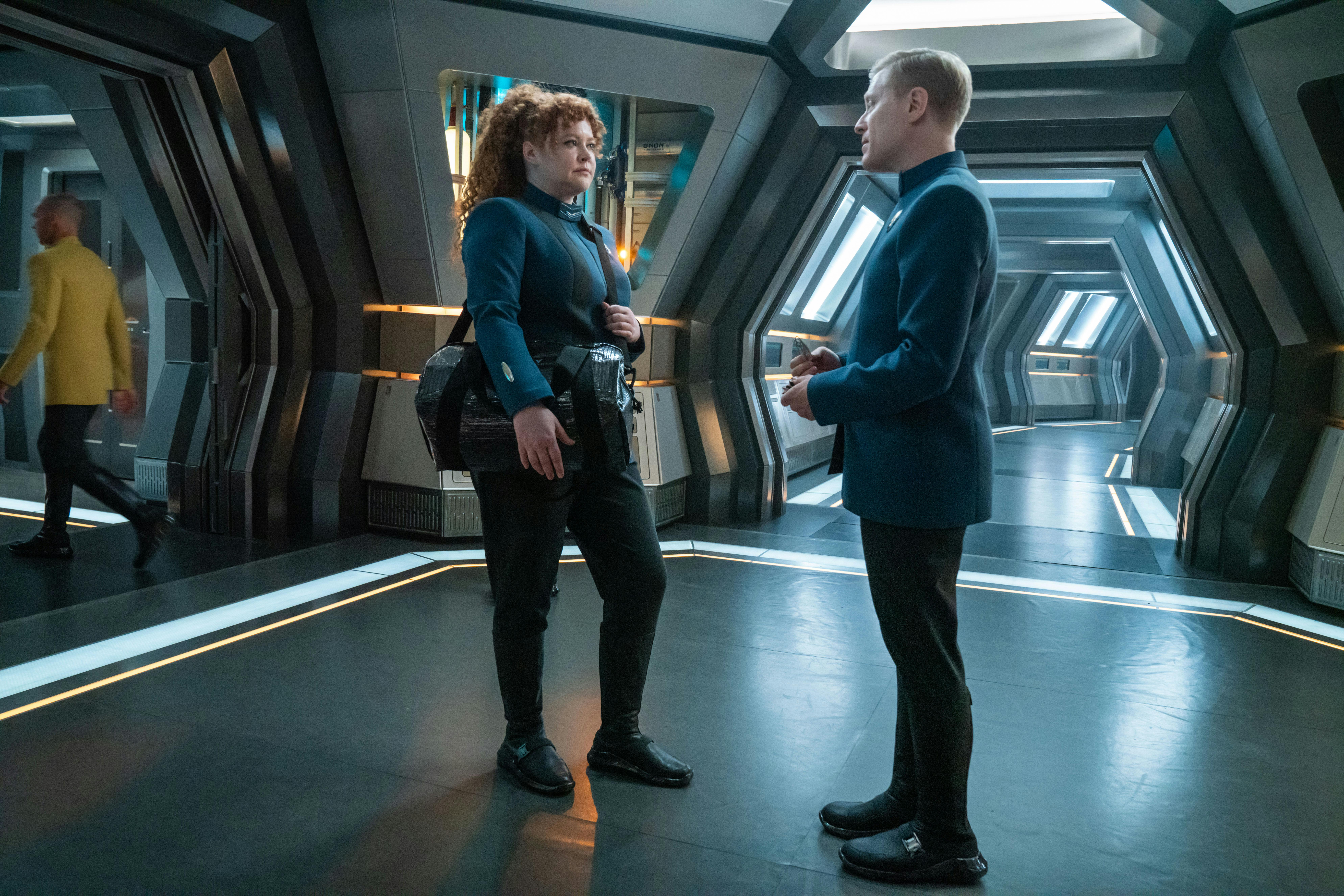 Carrying a go-bag, Tilly approaches Stamets in a Discovery corridor in 'Erigah'