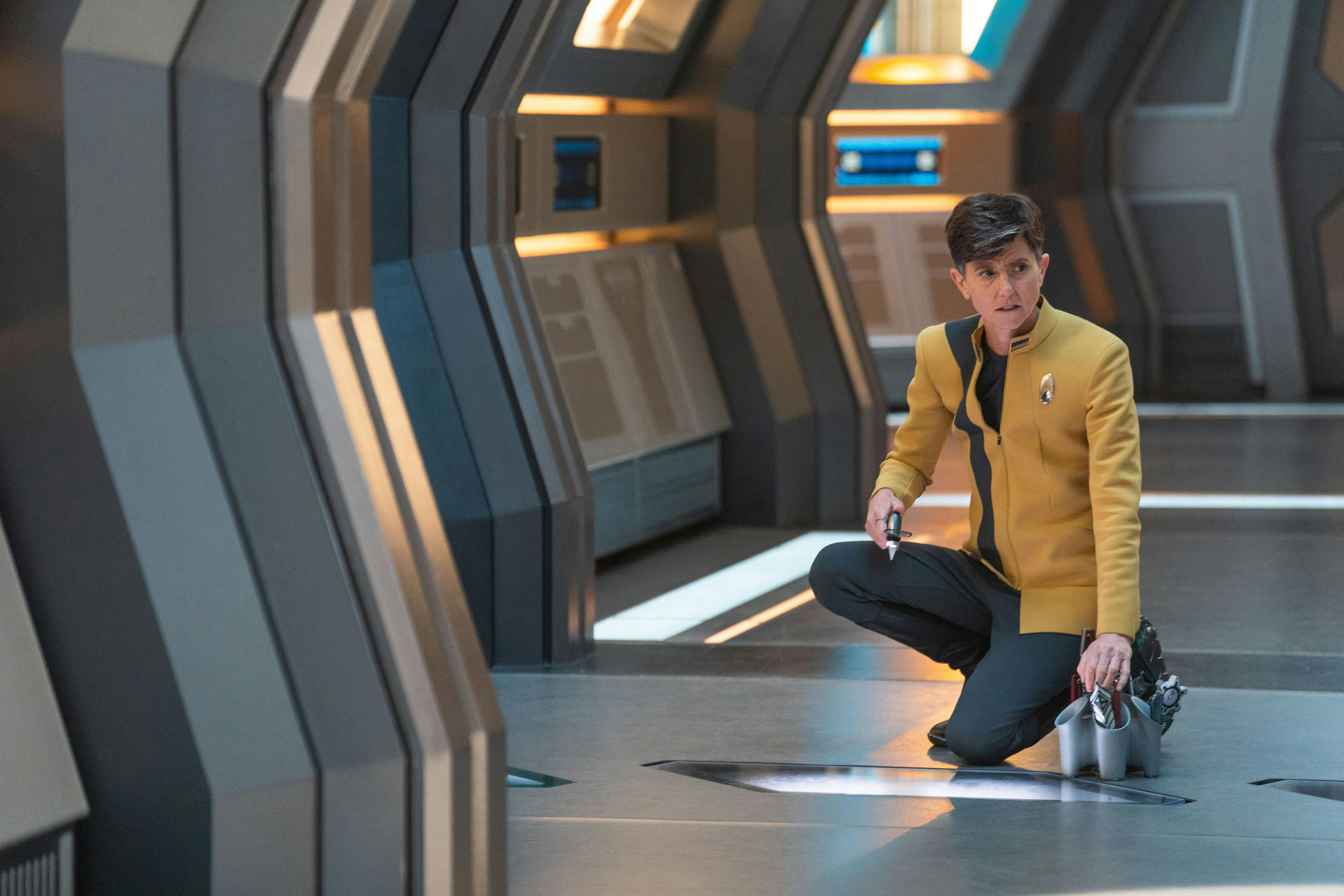 Jett Reno crouches at a panel in a Discovery corridor in 'Erigah'