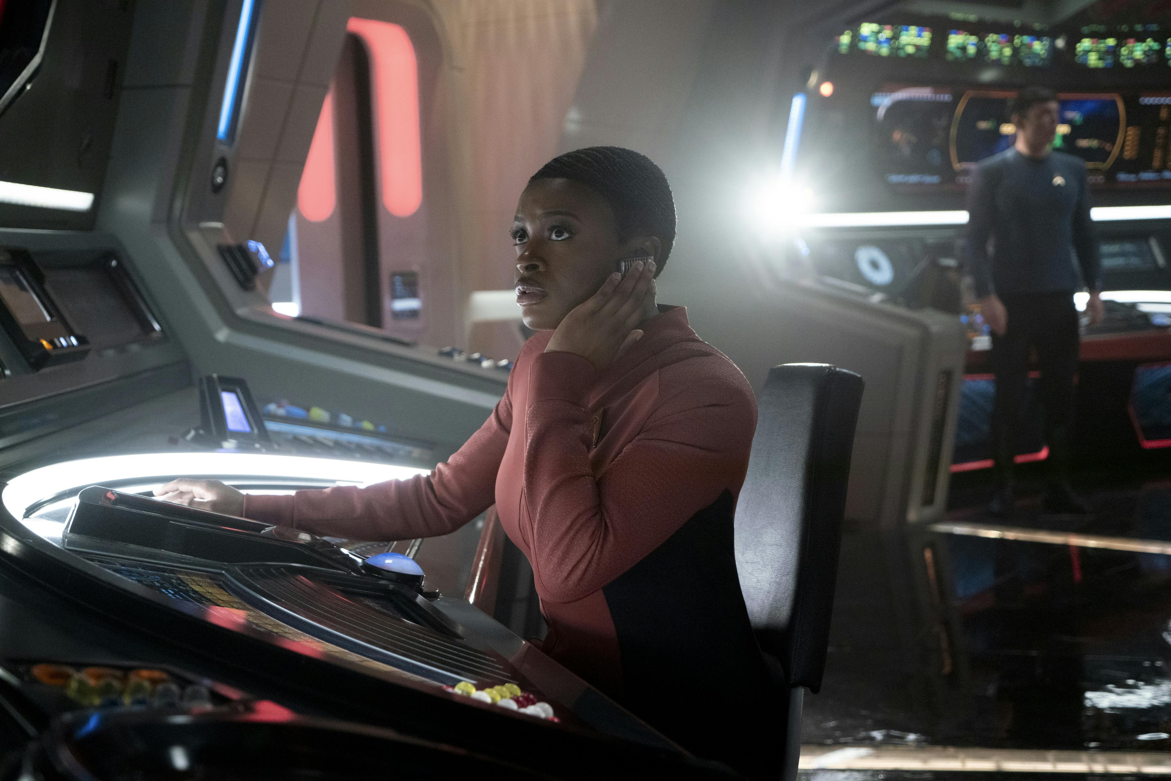 Uhura, sitting at her comms station, picks up on Batel's distress call from the surface of Parnassus Beta as Spock stands up alarmed at his station behind her in 'Hegemony'