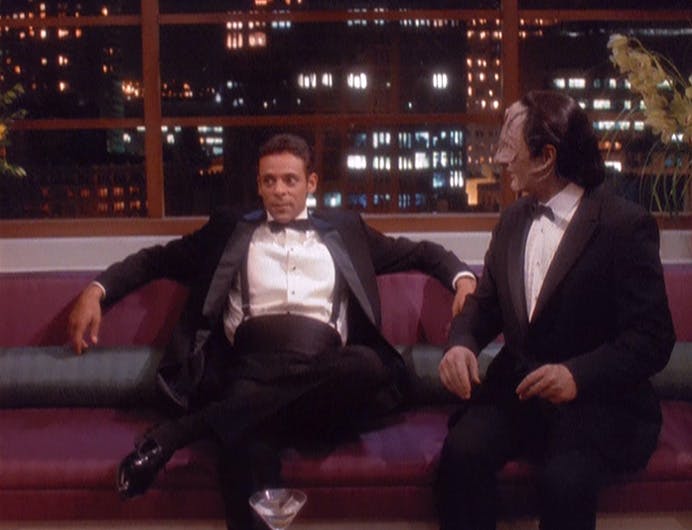 In the holosuite, Bashir leans back with arms resting on the couch as Garak sits beside him in 'Our Man Bashir'