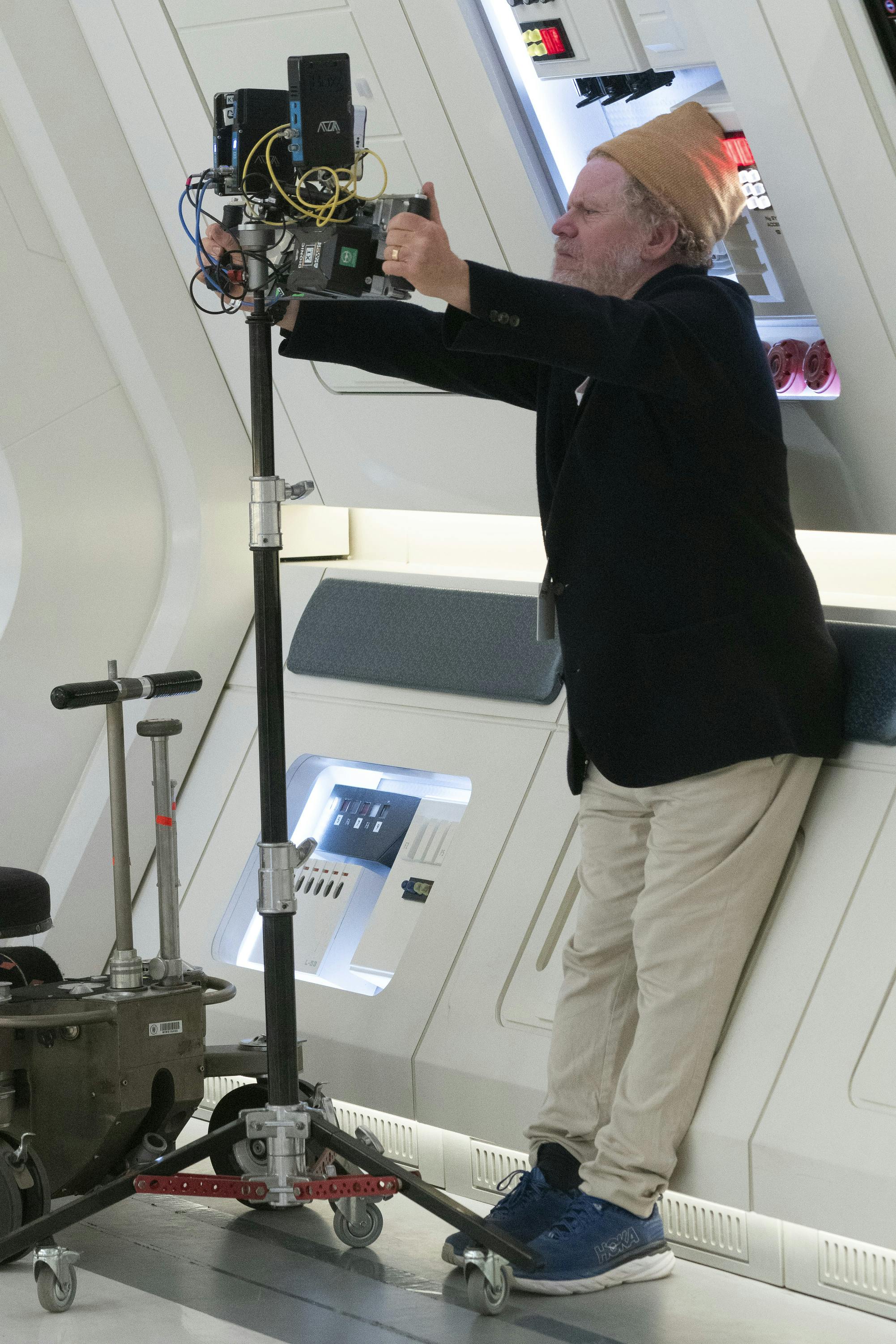 Behind-the-scenes of 'Subspace Rhapsody' with director Dermott Downs gripping a camera while leaning against the corridor set wall