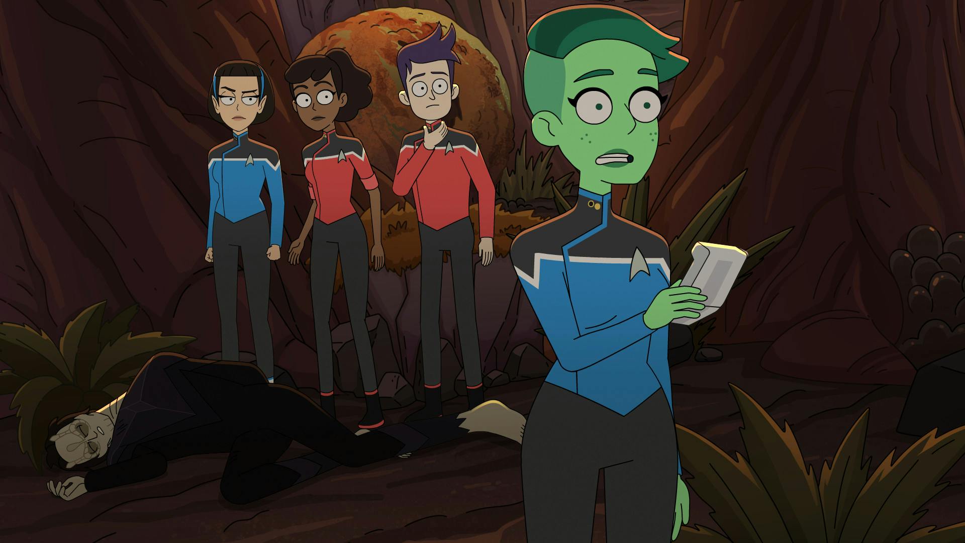 With an unconscious Cardassian at their feet, T'Lyn, Mariner, and Boimler look over at Tendi who uses her scanner to assess the situation on Sherbal V in 'The Inner Fight'