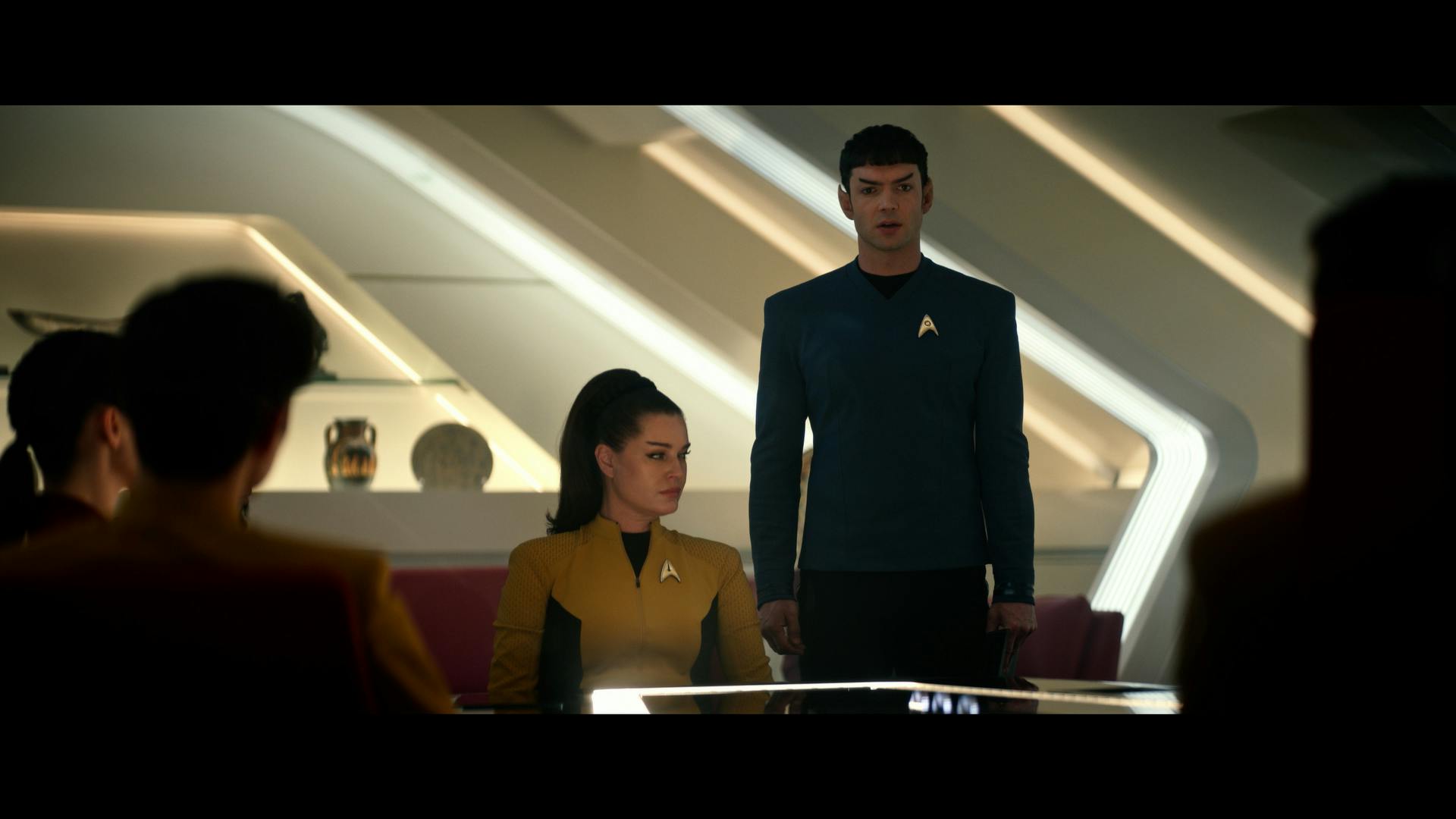 In Pike's ready room, Spock faces the conference table where Number One, La'An, Sam Kirk, and Pike are seated in 'Subspace Rhapsody'