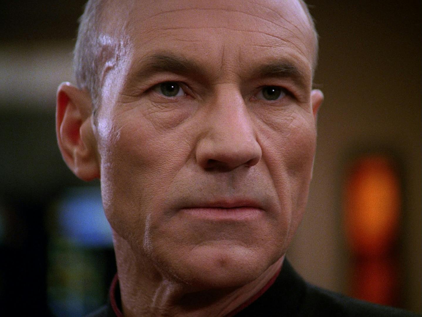 Close-up of Jean-Luc Picard who stands and sternly assesses the threat on the viewscreen in front of him in 'The Best of Both Worlds, Part I'