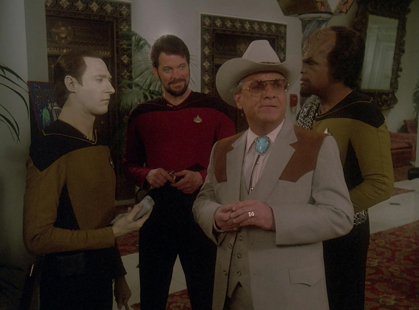 Data, Riker, and Worf arrive at Hotel Royale curious about where they've landed as Data lifts his tricorder towards Sam Anderson in 'The Royale'