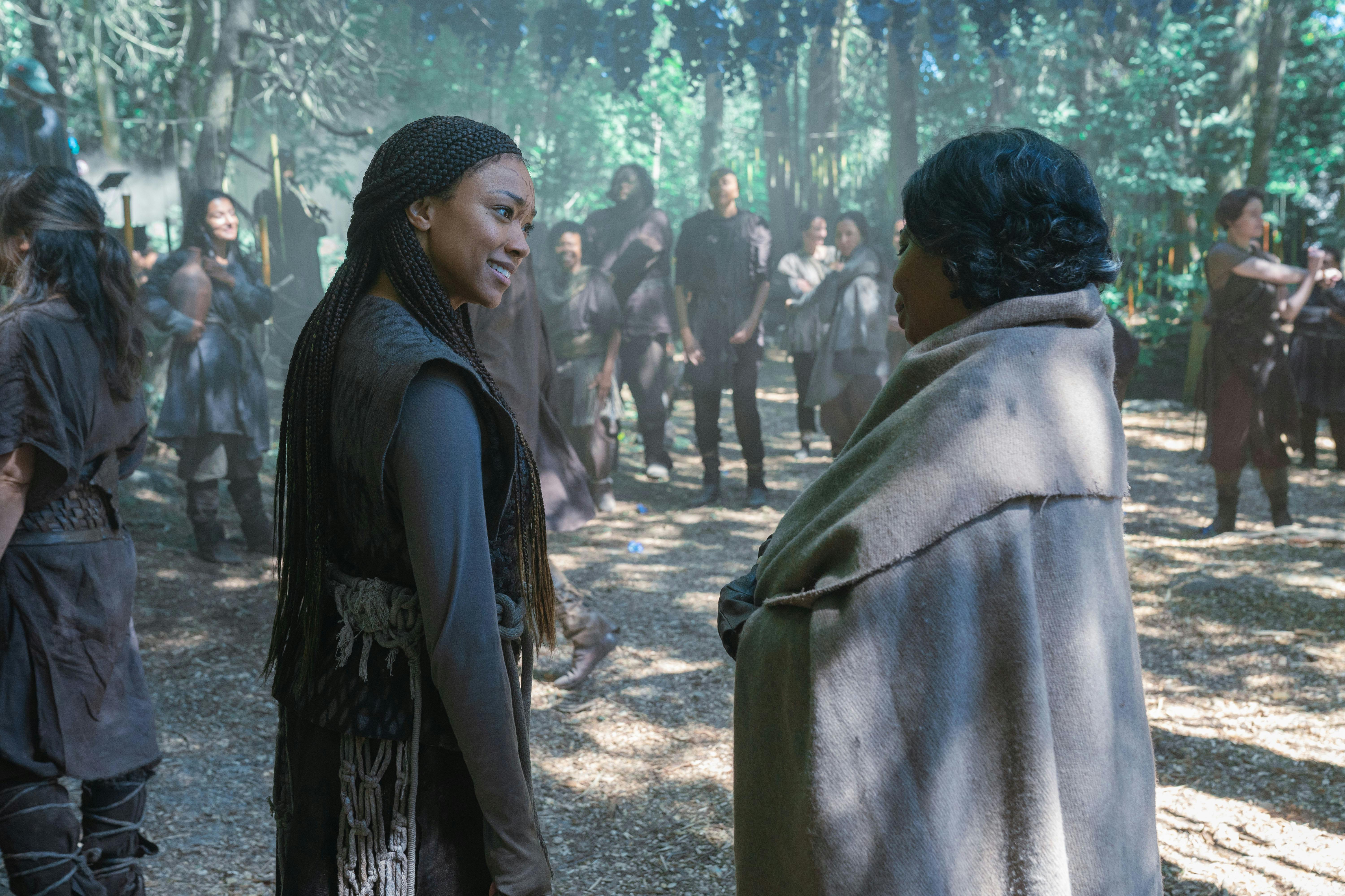 Dressed as native, Michael Burnham turns towards  and smiles at Anorah bundled in a blanket on the surface of Halem'no in 'Whistlespeak'