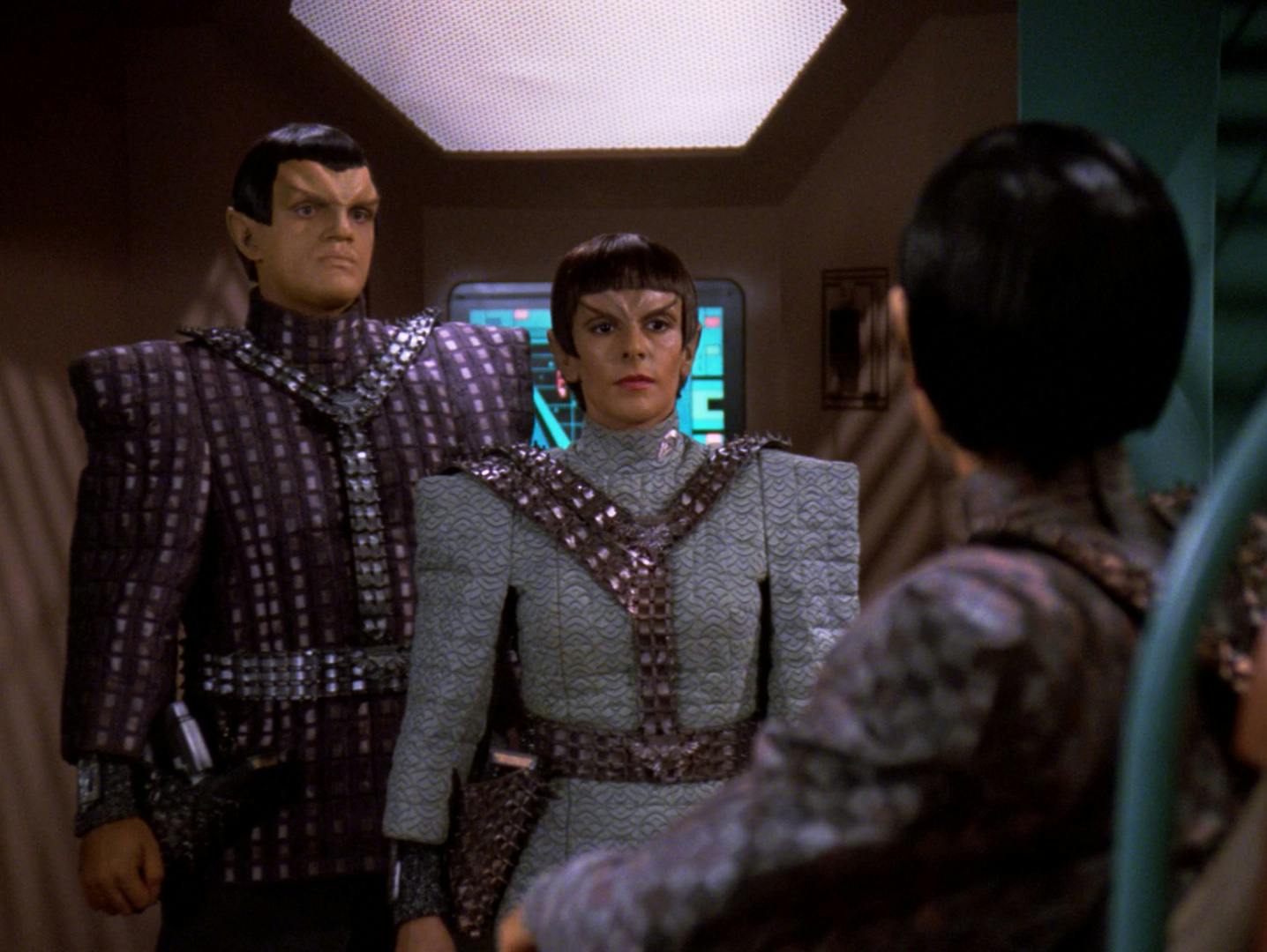 Aboard the Romulan warbird Khazara, Subcommander N'Vek and Deanna Troi poses as Major Rakal of the Tal Shiar stand side-by-side in front of Commander Toreth in 'Face of the Enemy'