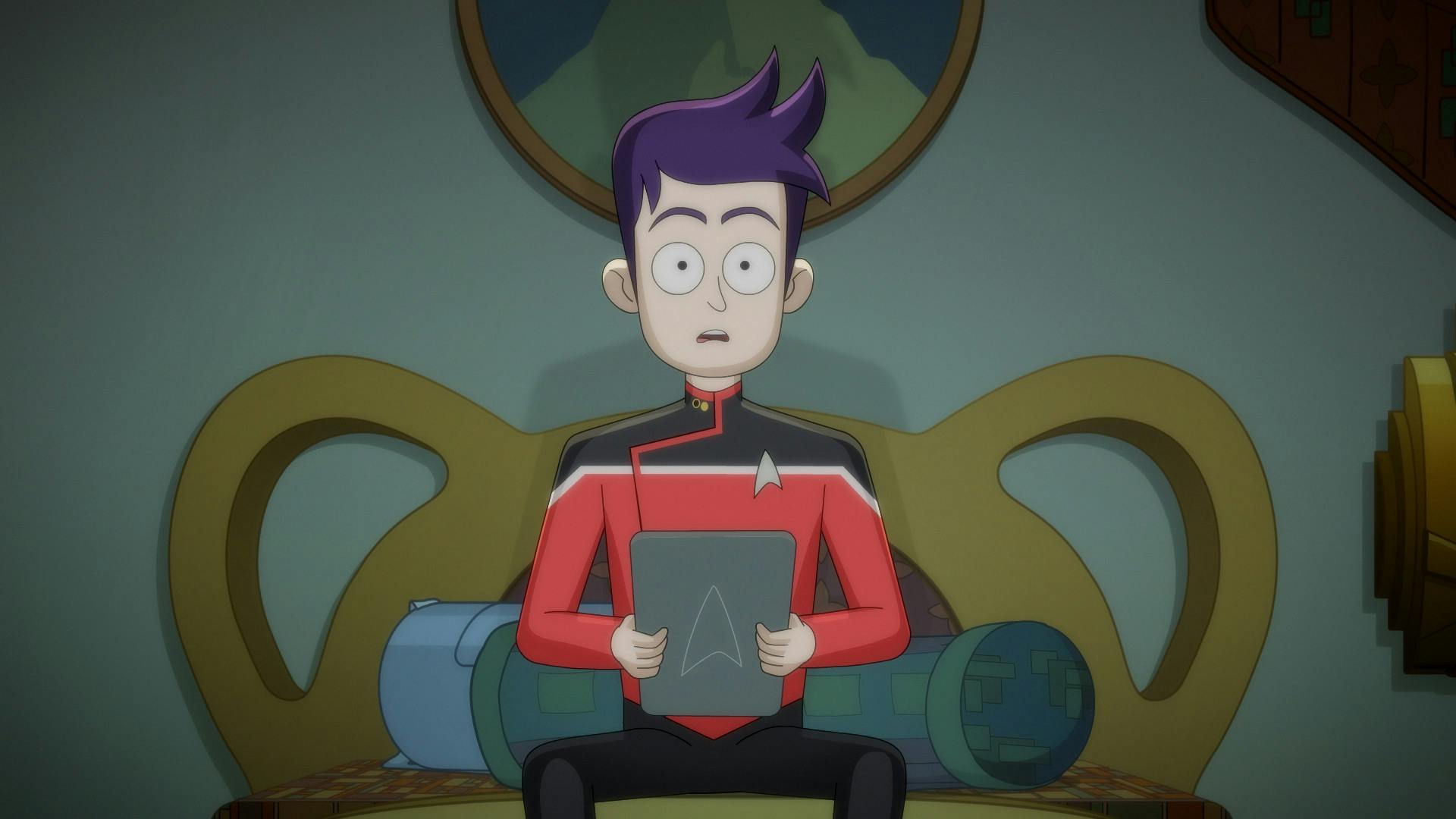 In his Ferenginar hotel room, Boimler sits at the edge of his bed, engrossed in Ferengi TV while holding his PADD in 'Parth Ferengi's Heart Place'