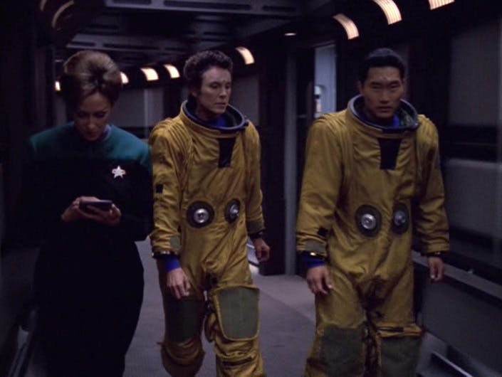 Commander Terrina and pilot Gotana-Retz walk beside a Starfleet officer aboard Voyager in 'Blink of an Eye'